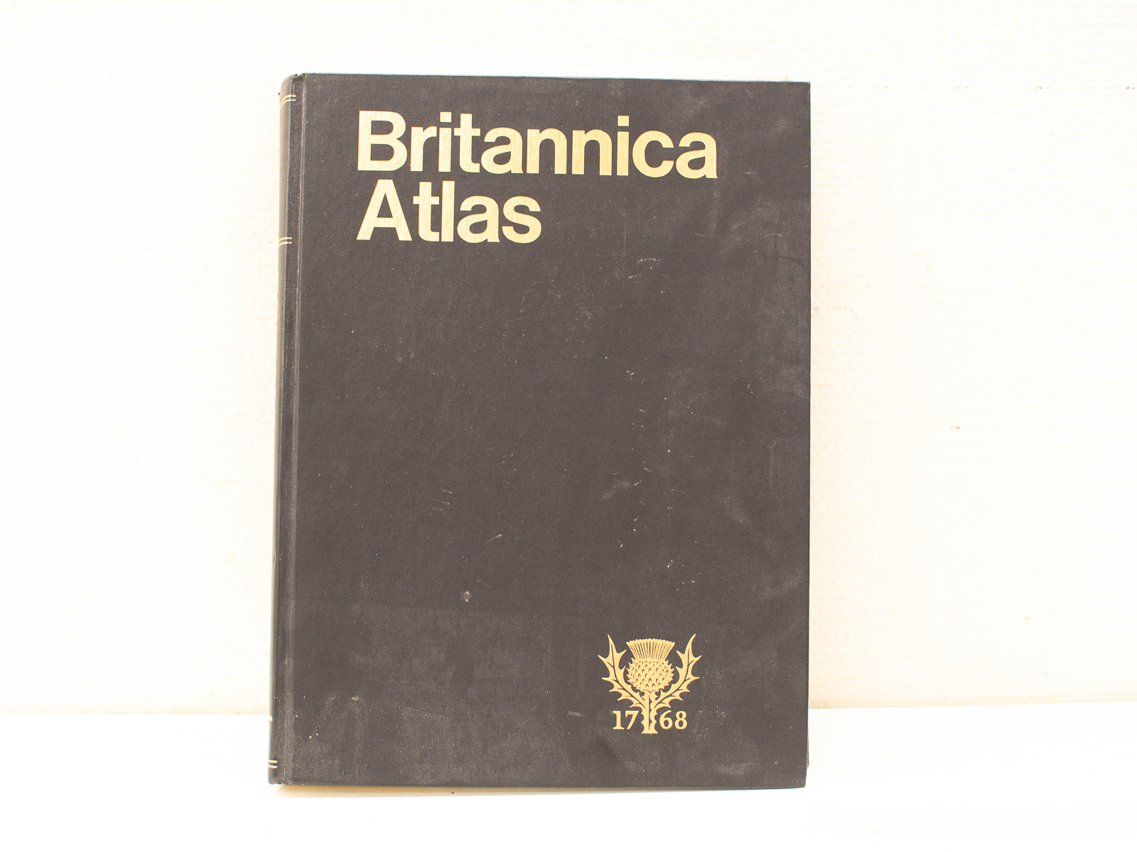 Vintage Britannica Atlas: Elegant black cover, gold lettering, thistle emblem, historical map reference from 1768.