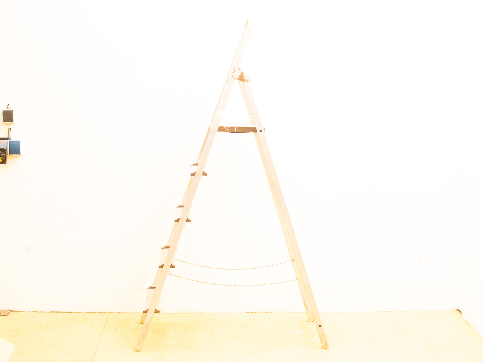 Simple wooden A-frame ladder against a bright white background, emphasizing minimalist design and functionality.