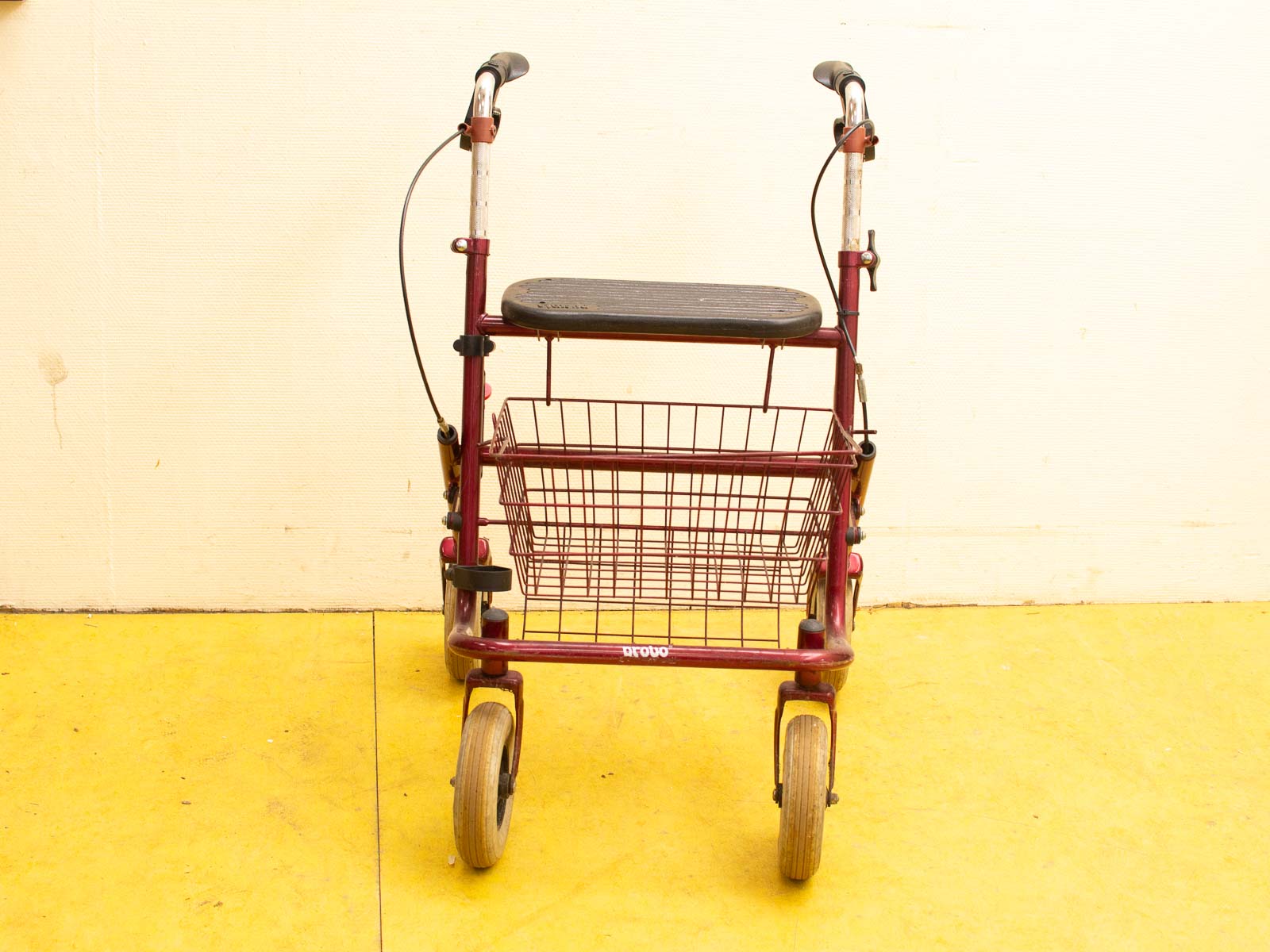 Burgundy mobility walker with seat, basket, and sturdy design for stability and convenience.