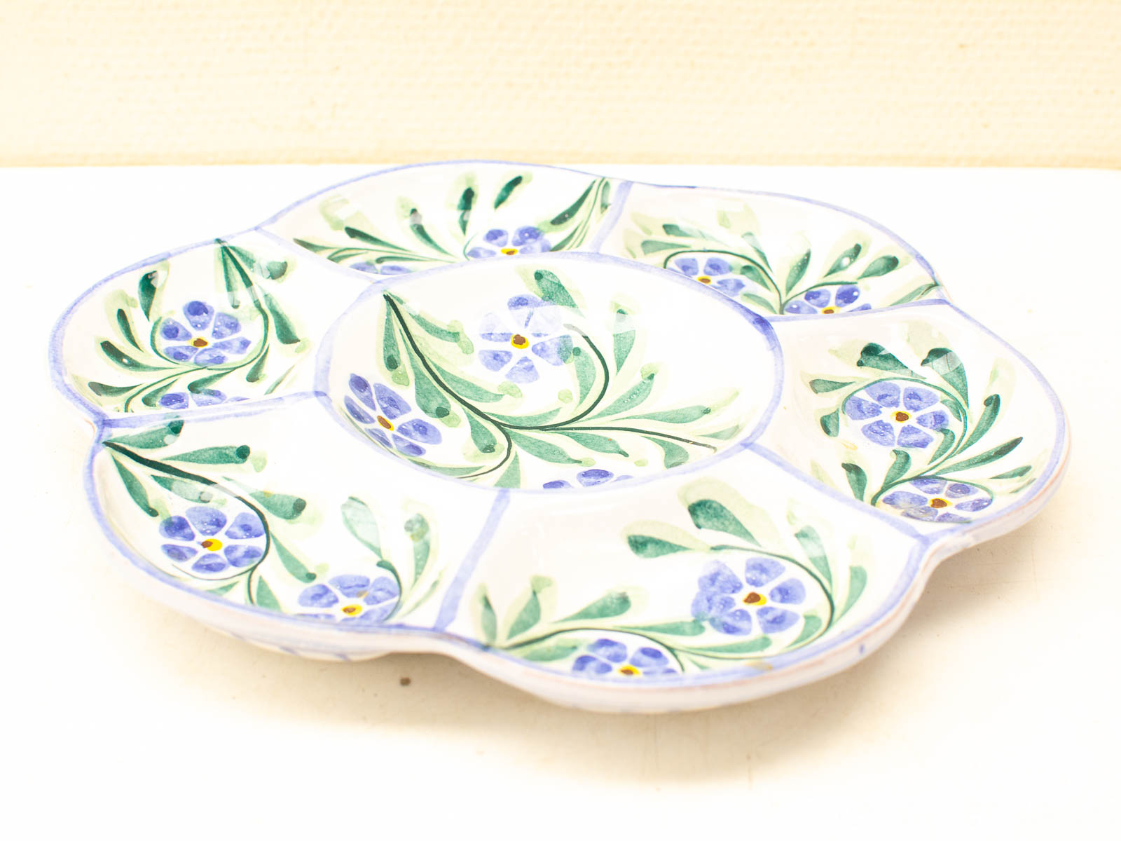 Elegant vintage ceramic plate with vibrant blue and green floral design and scalloped edge.