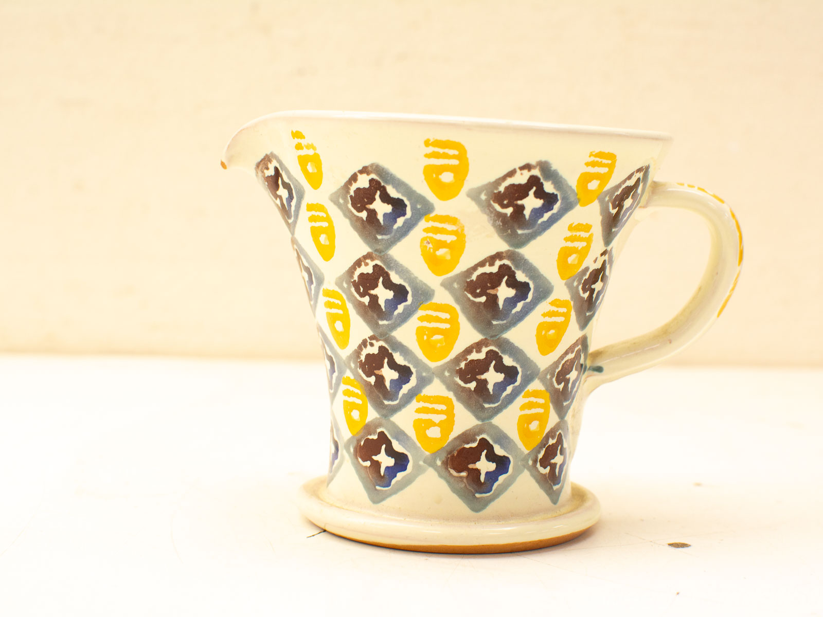 Colorful handmade ceramic jug with geometric diamond pattern, perfect for decor and pottery lovers.