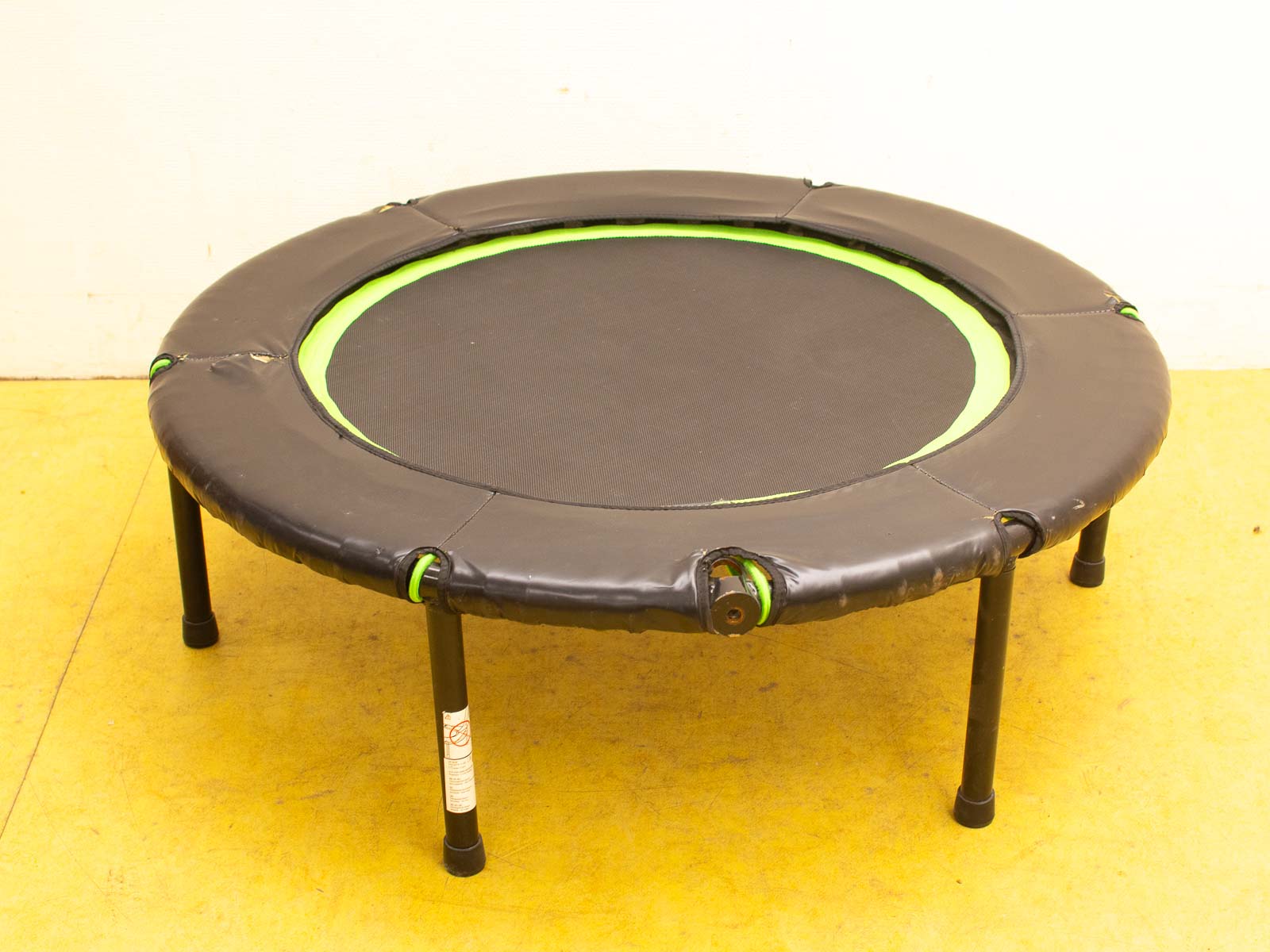 Indoor mini trampoline with black padding and green accents, perfect for small spaces and fitness.