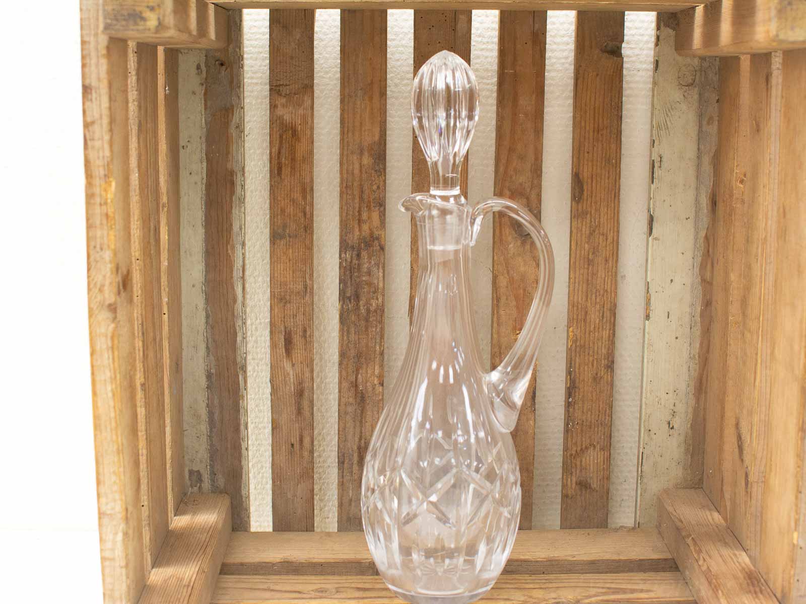 Elegant crystal decanter in rustic wooden crate, showcasing beauty and craftsmanship.