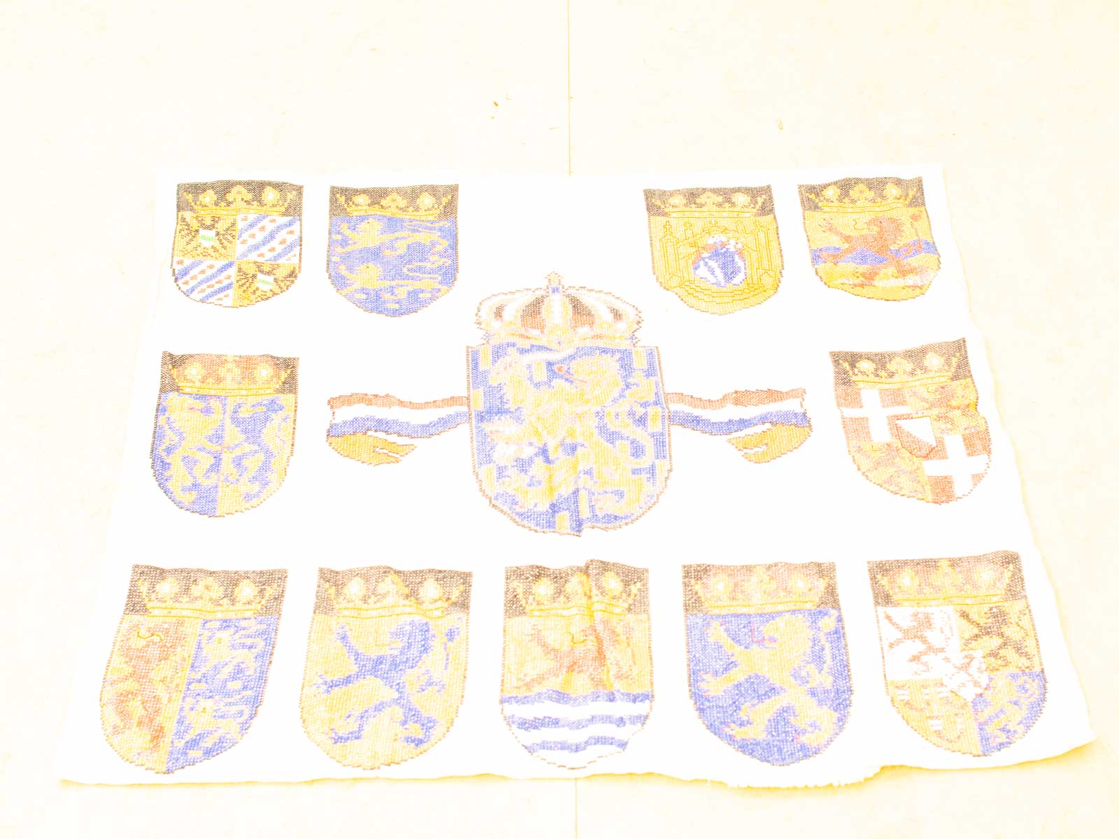 Vintage textile featuring heraldic shields and a central coat of arms in blue and gold.