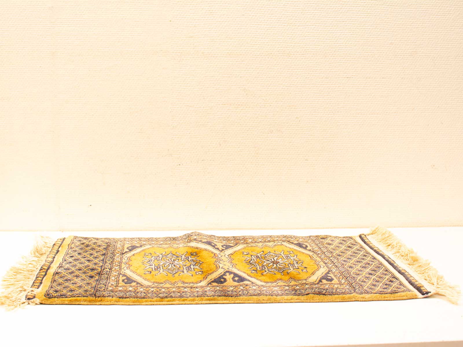 Elegant vintage rug with intricate octagonal pattern in warm gold, ochre, blue, and white.