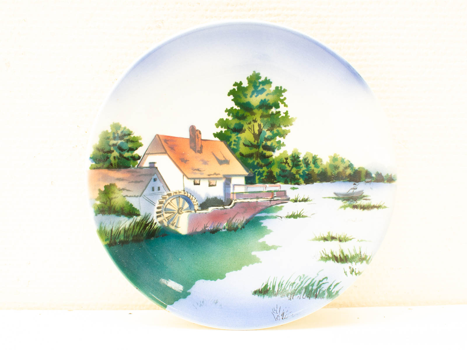 Charming cottage by the water with a rustic wheel, surrounded by serene nature.