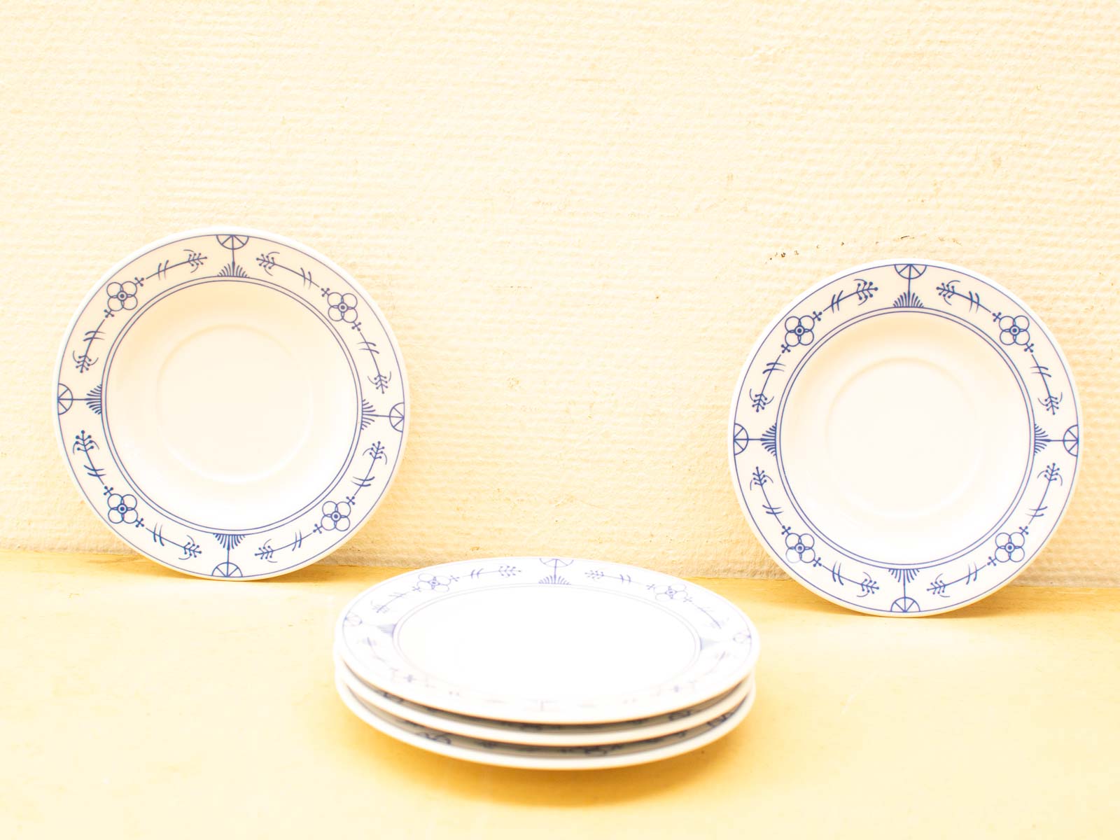 Elegant blue-patterned decorative plates arranged beautifully against a warm yellow backdrop.