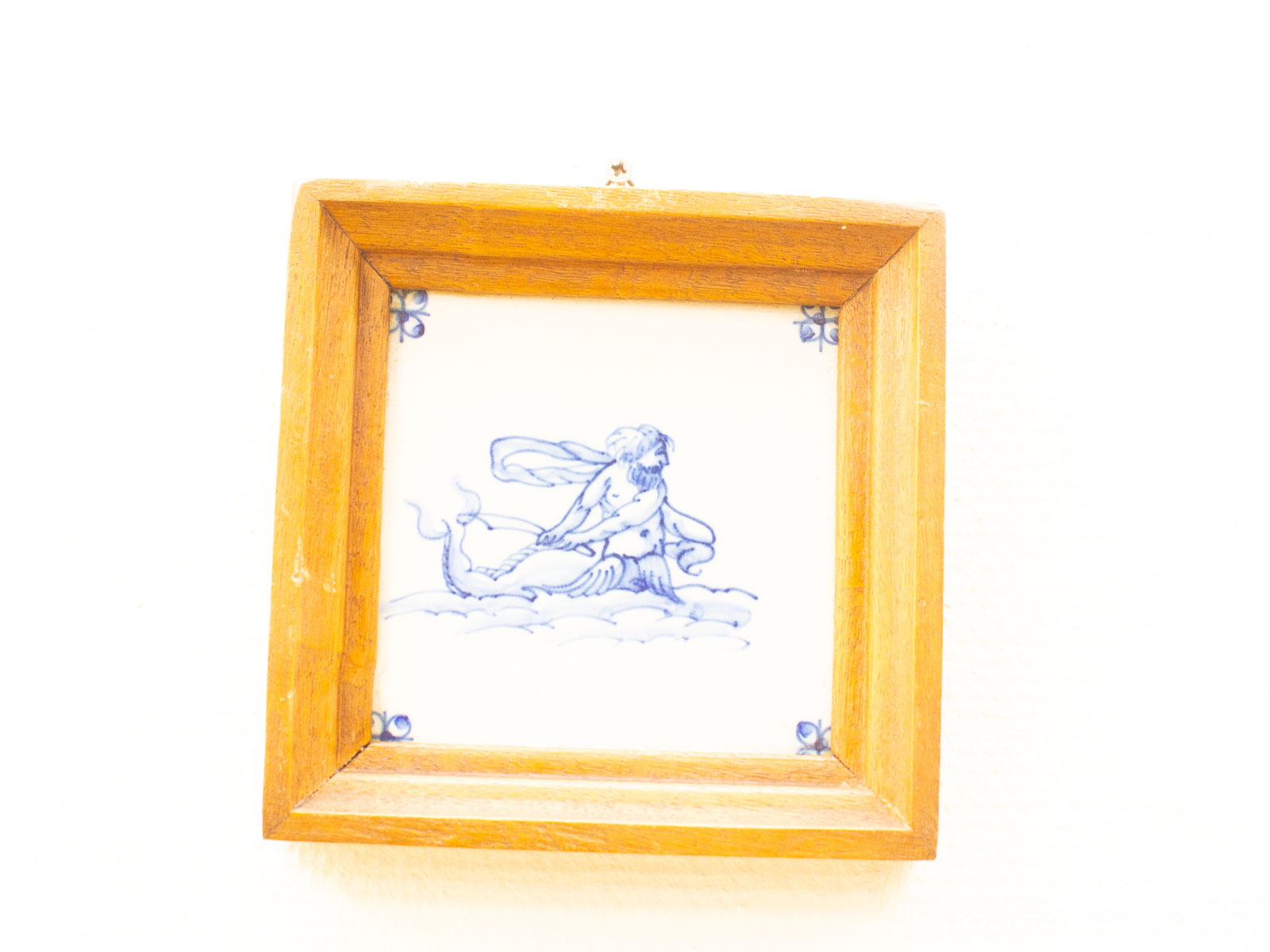 Vintage ceramic tile art featuring a mythological figure in blue and white, elegantly framed.