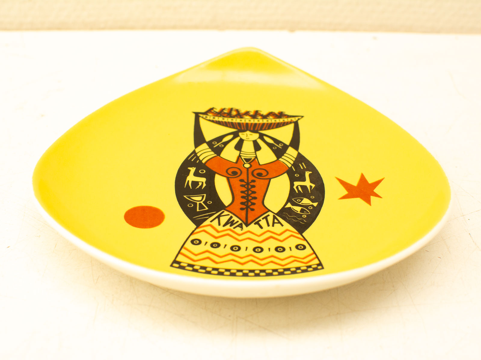 Vibrant yellow decorative plate featuring a woman with a basket and intricate geometric patterns.