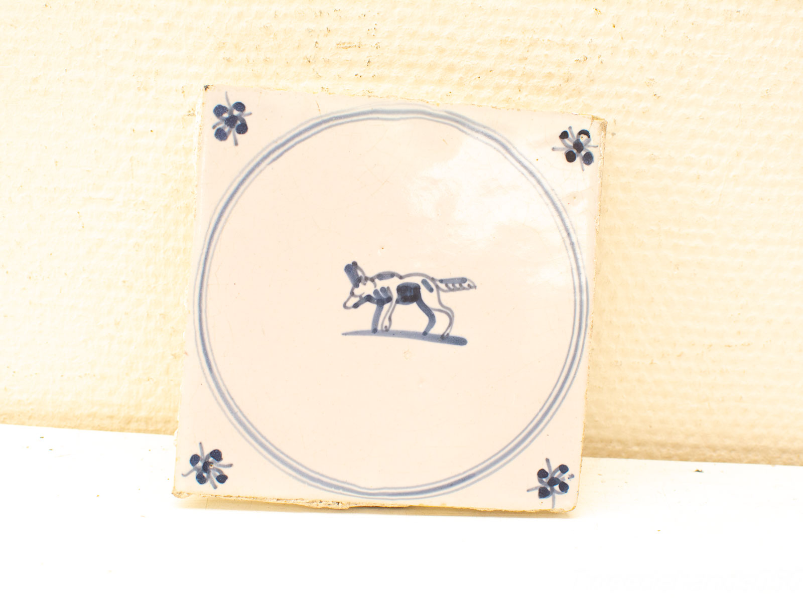 Whimsical blue dog ceramic tile with floral accents, perfect for charming home decor.