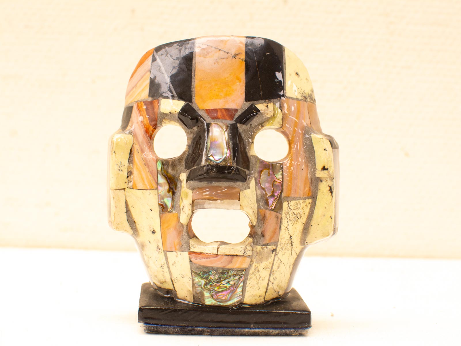 Vibrant mask sculpture of colored stones and shells, showcasing intricate craftsmanship and cultural significance.