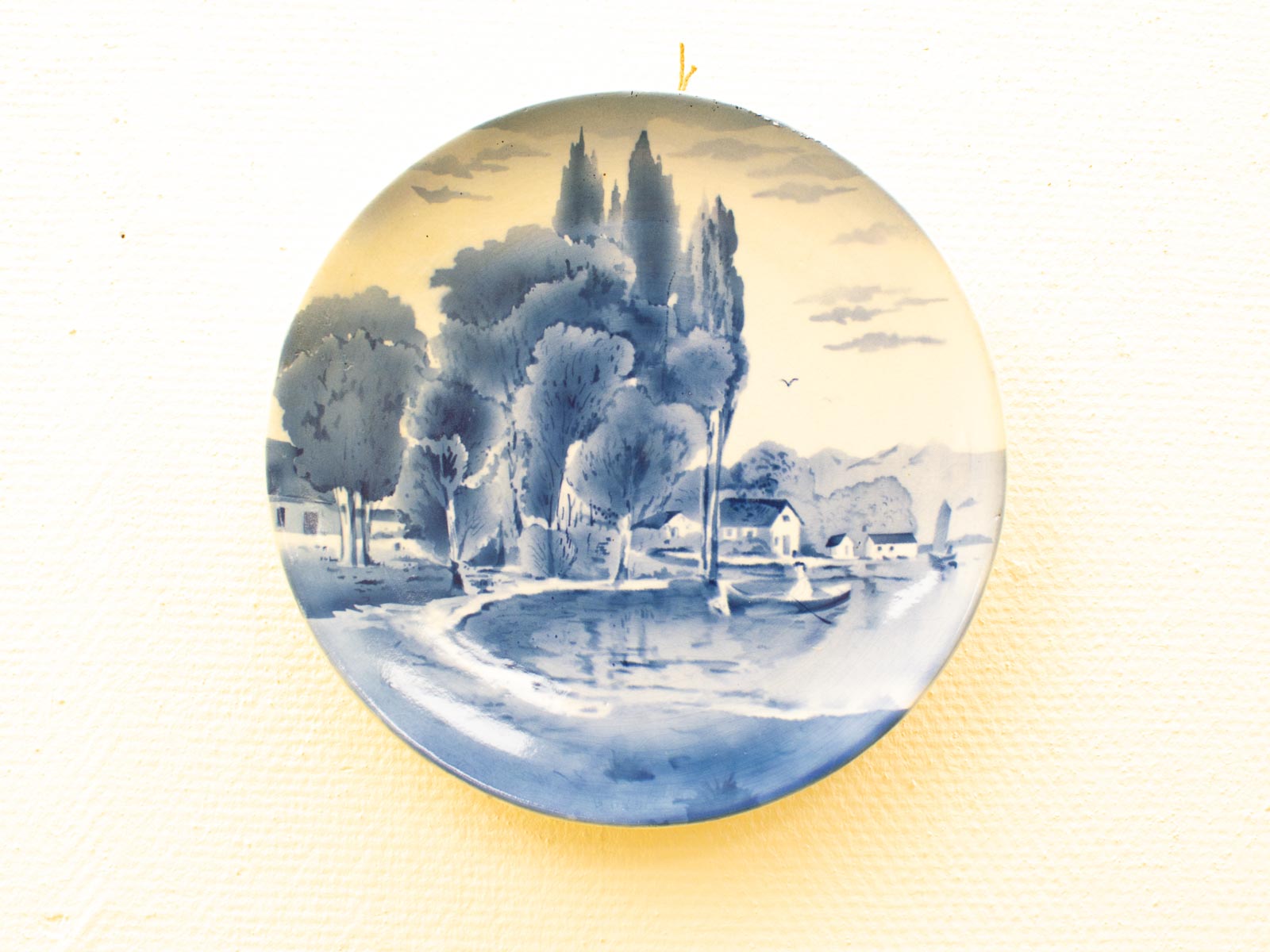 Tranquil blue and white decorative plate featuring a serene lakeside landscape scene.