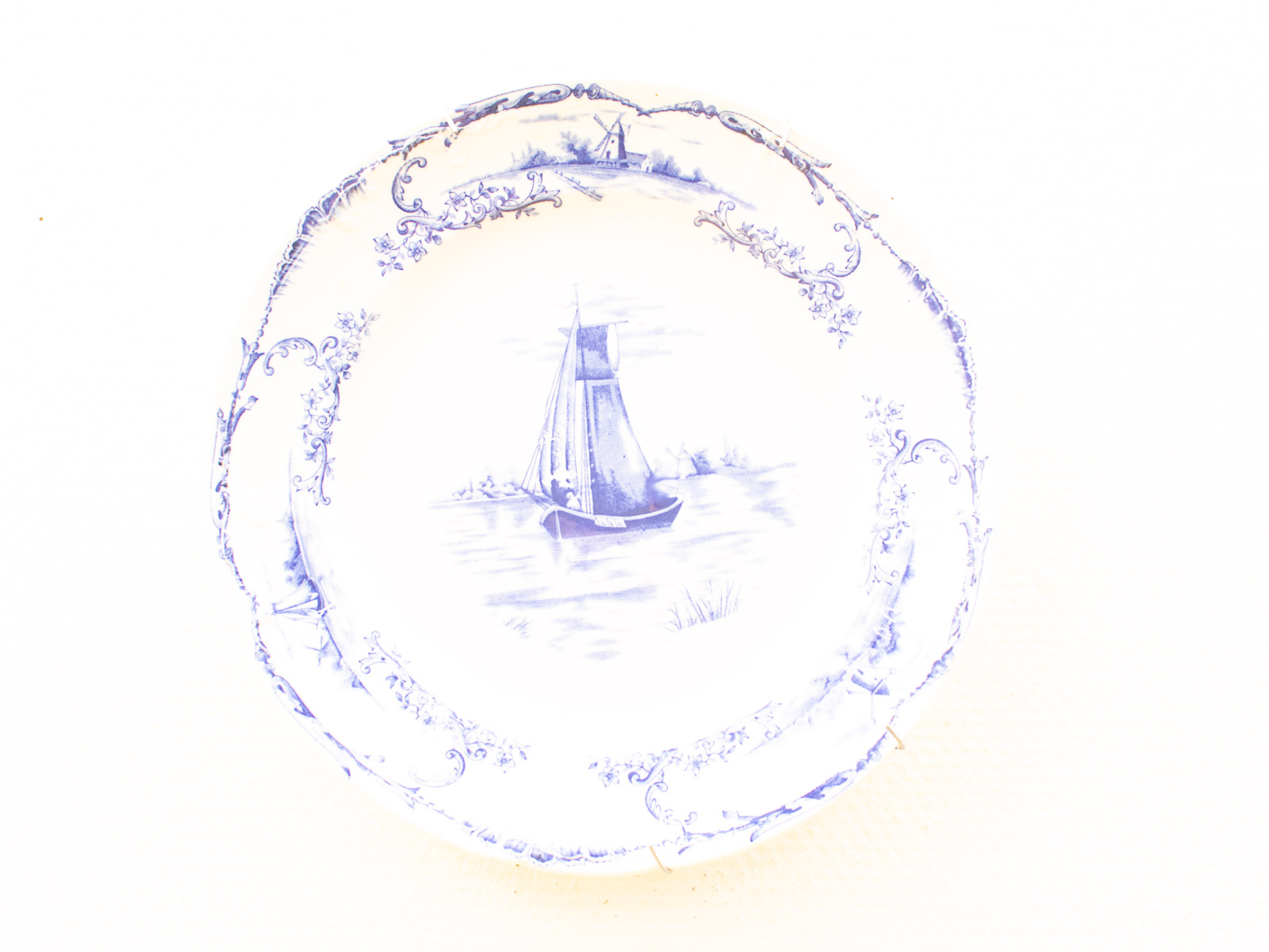 Elegant porcelain plate with sailboat scene and intricate blue floral designs. Perfect for collectors.