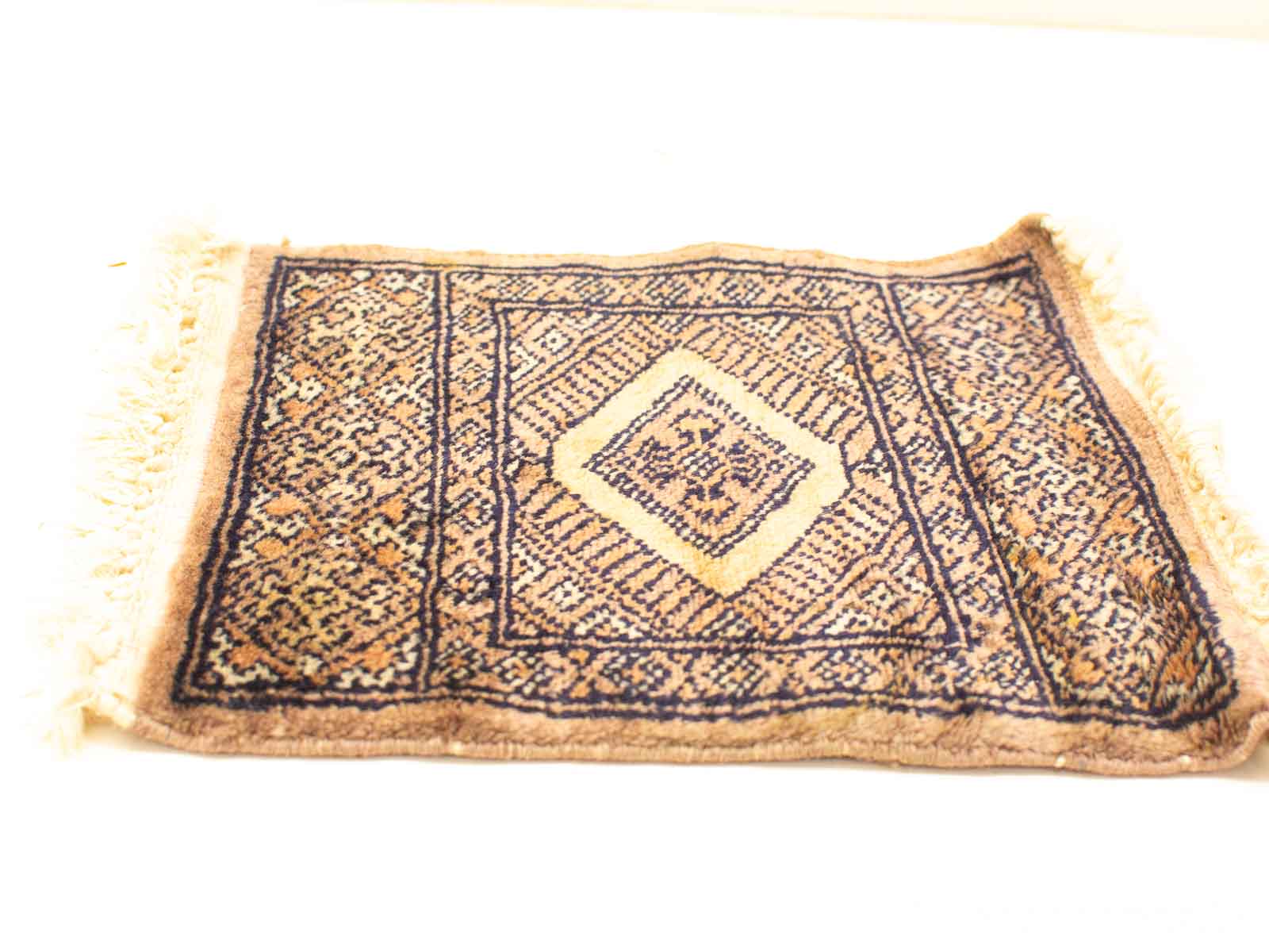 Elegant vintage rug with diamond pattern in warm tan, blue, and brown hues.