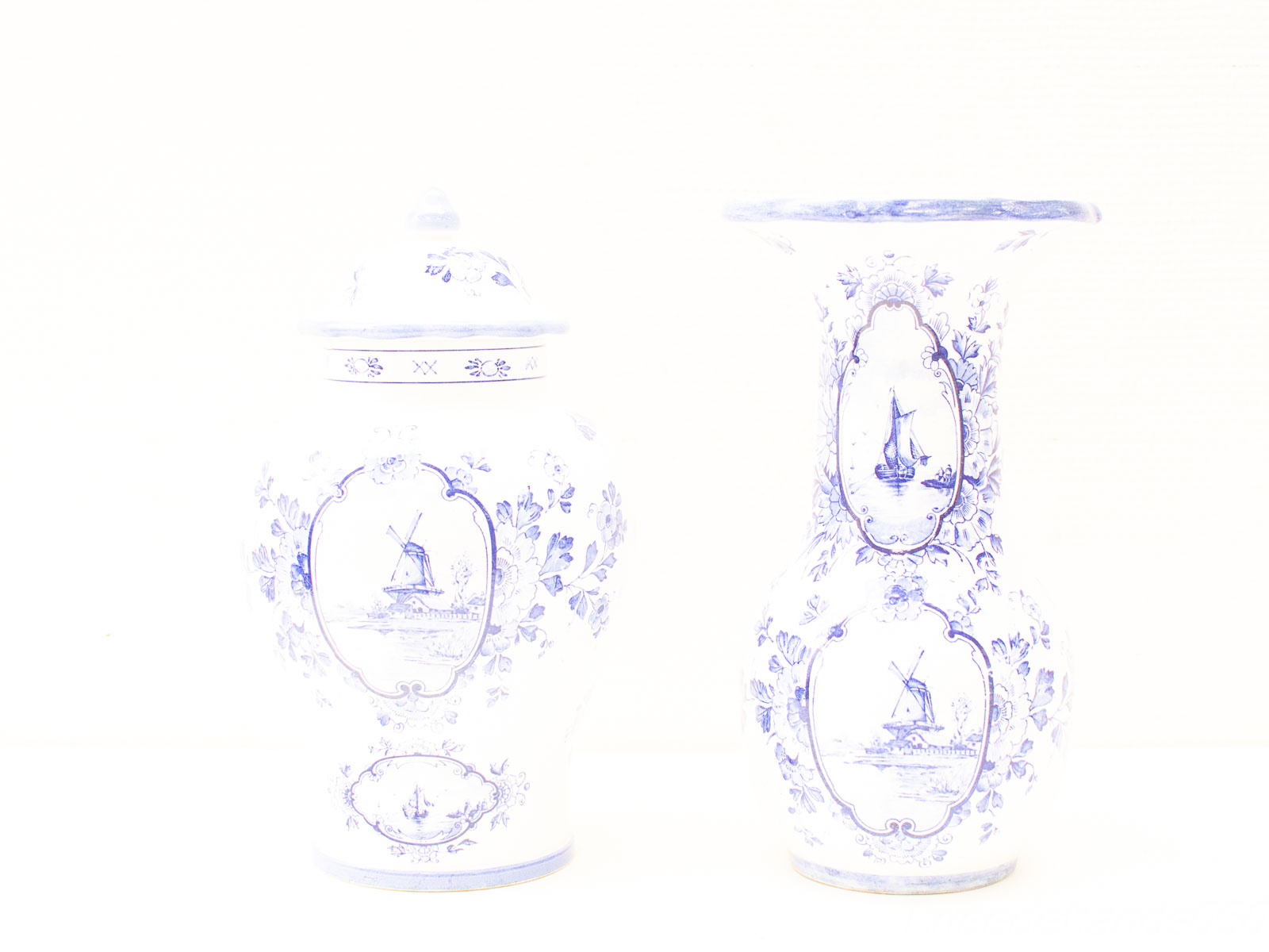 Elegant blue-and-white porcelain vases featuring floral designs, a windmill, and a sailboat.