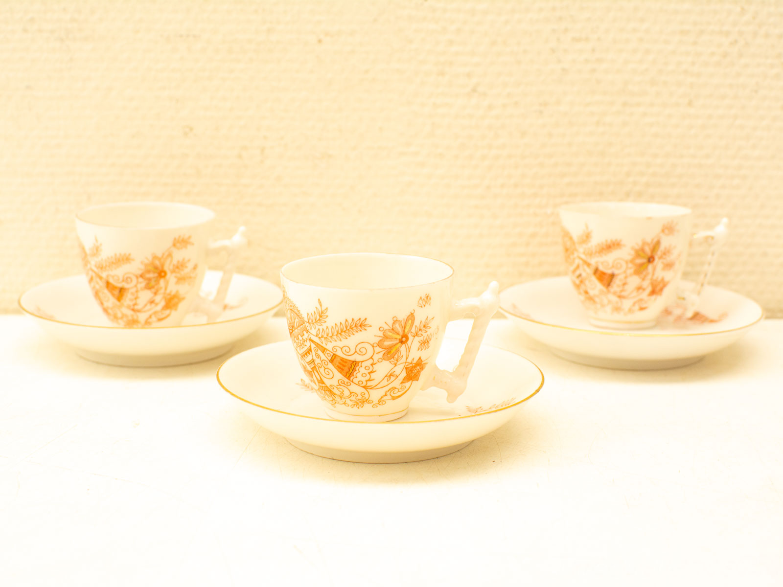 Elegant vintage porcelain tea cups and saucers with warm orange floral designs for charming gatherings.