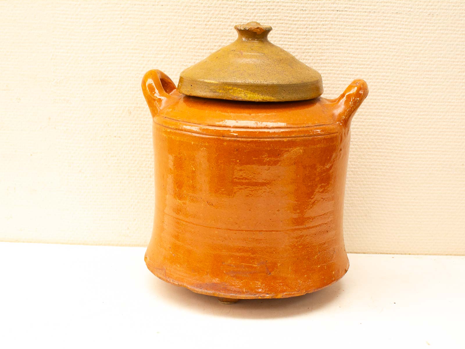 Vintage terracotta pot with lid and handles, perfect for storage or rustic kitchen decor.