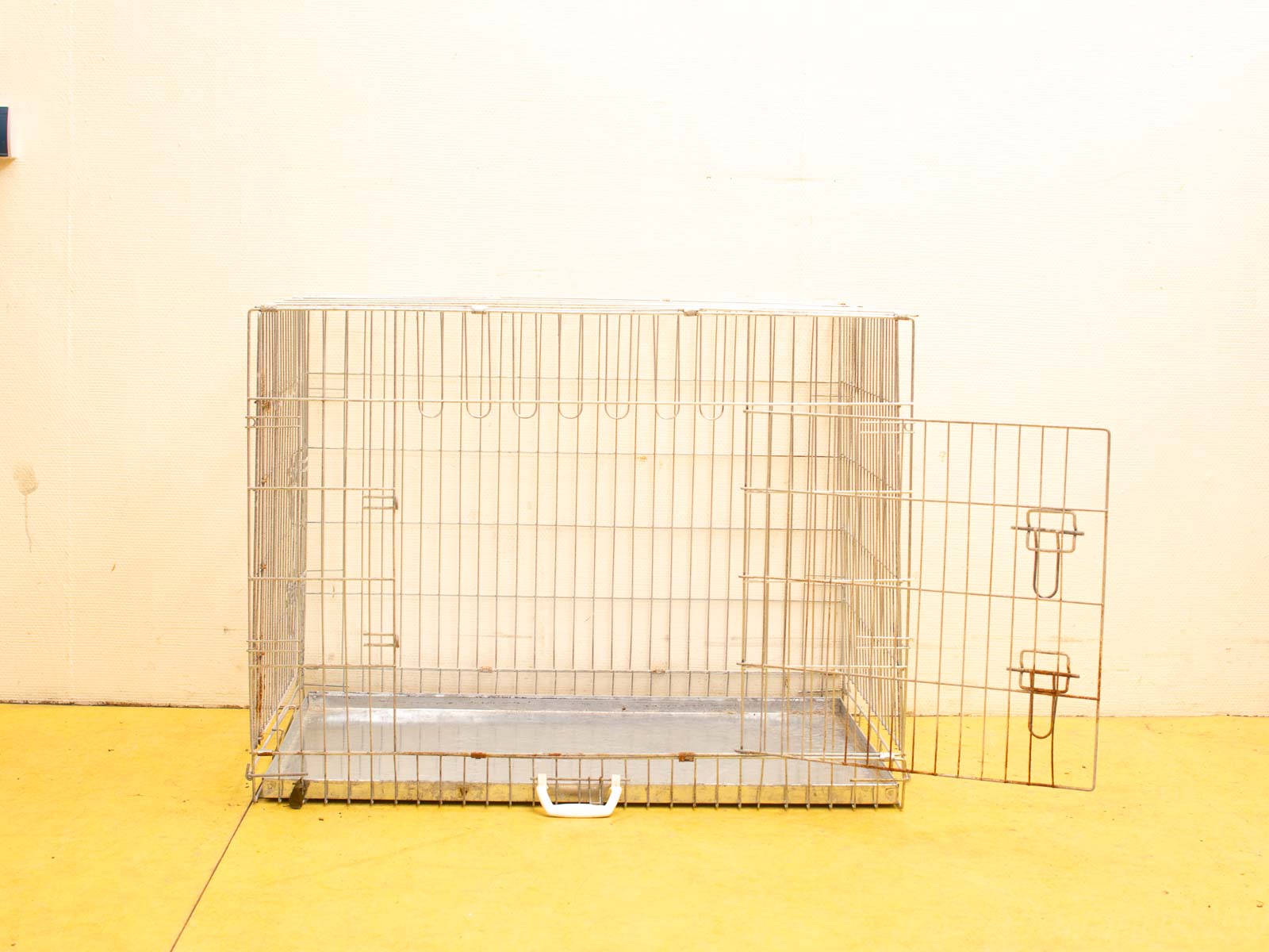 High-quality second-hand wire dog crate on vibrant yellow floor, ideal for training and travel.