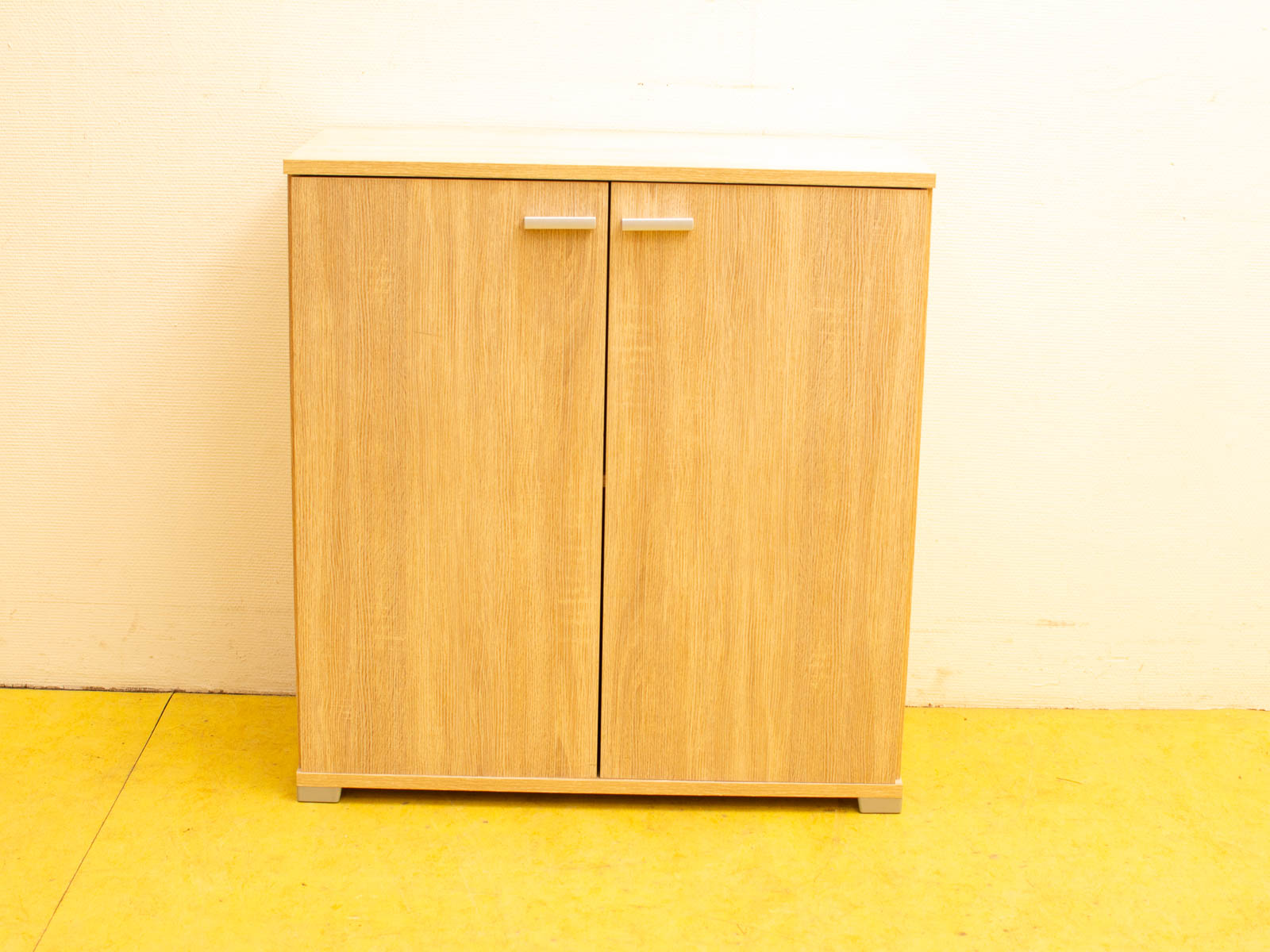 Modern wooden cabinet with storage, light finish, and sleek silver handles for stylish organization.