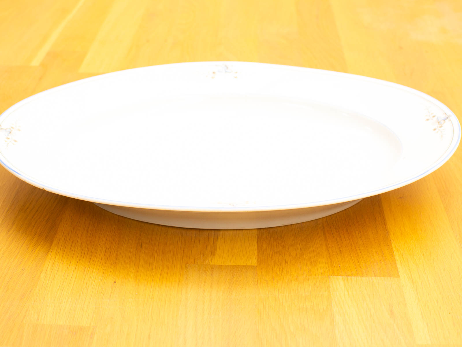 Elegant white oval serving platter on a warm wooden table, perfect for special occasions.