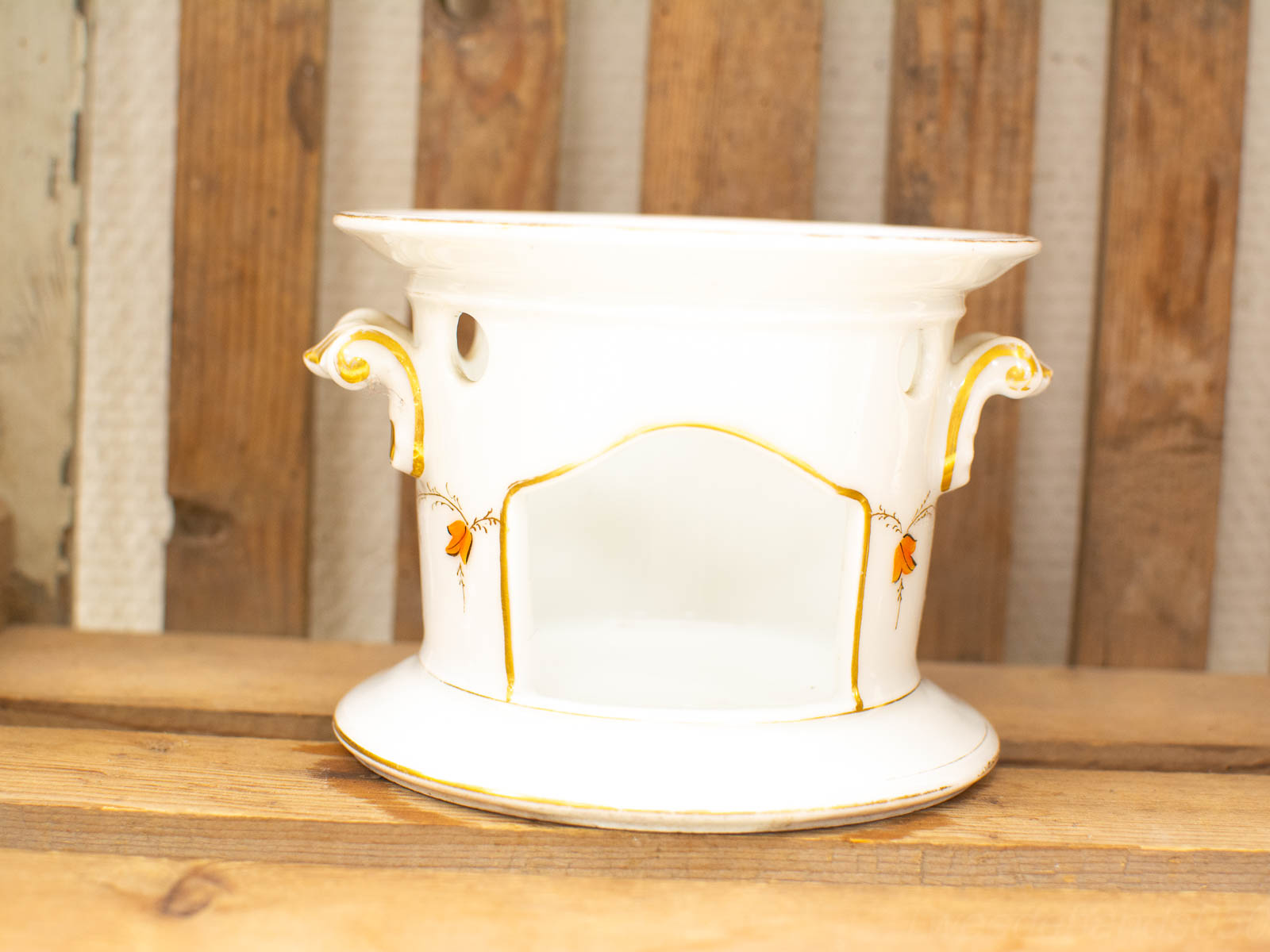 Elegant porcelain planter with golden accents, scroll handles, and drainage holes for stylish decoration.