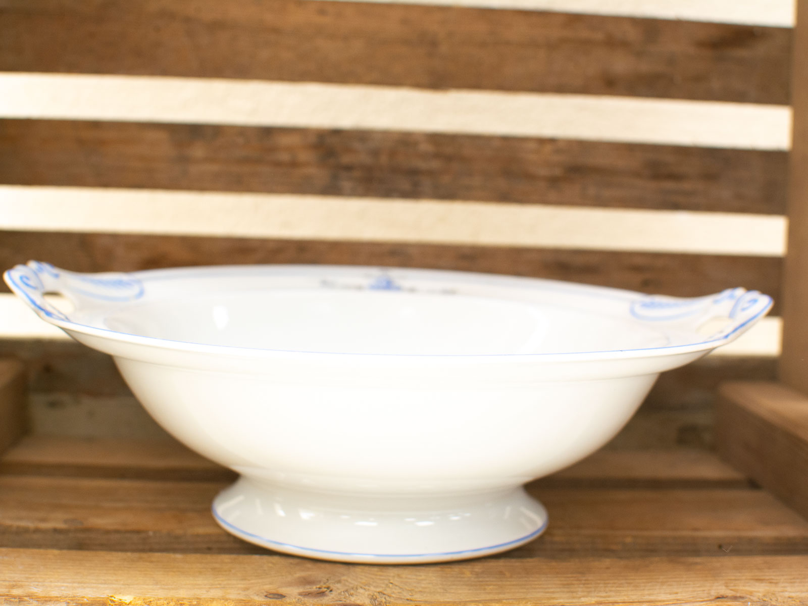 Elegant porcelain bowl with blue accents on a rustic wooden shelf. Perfect for serving.