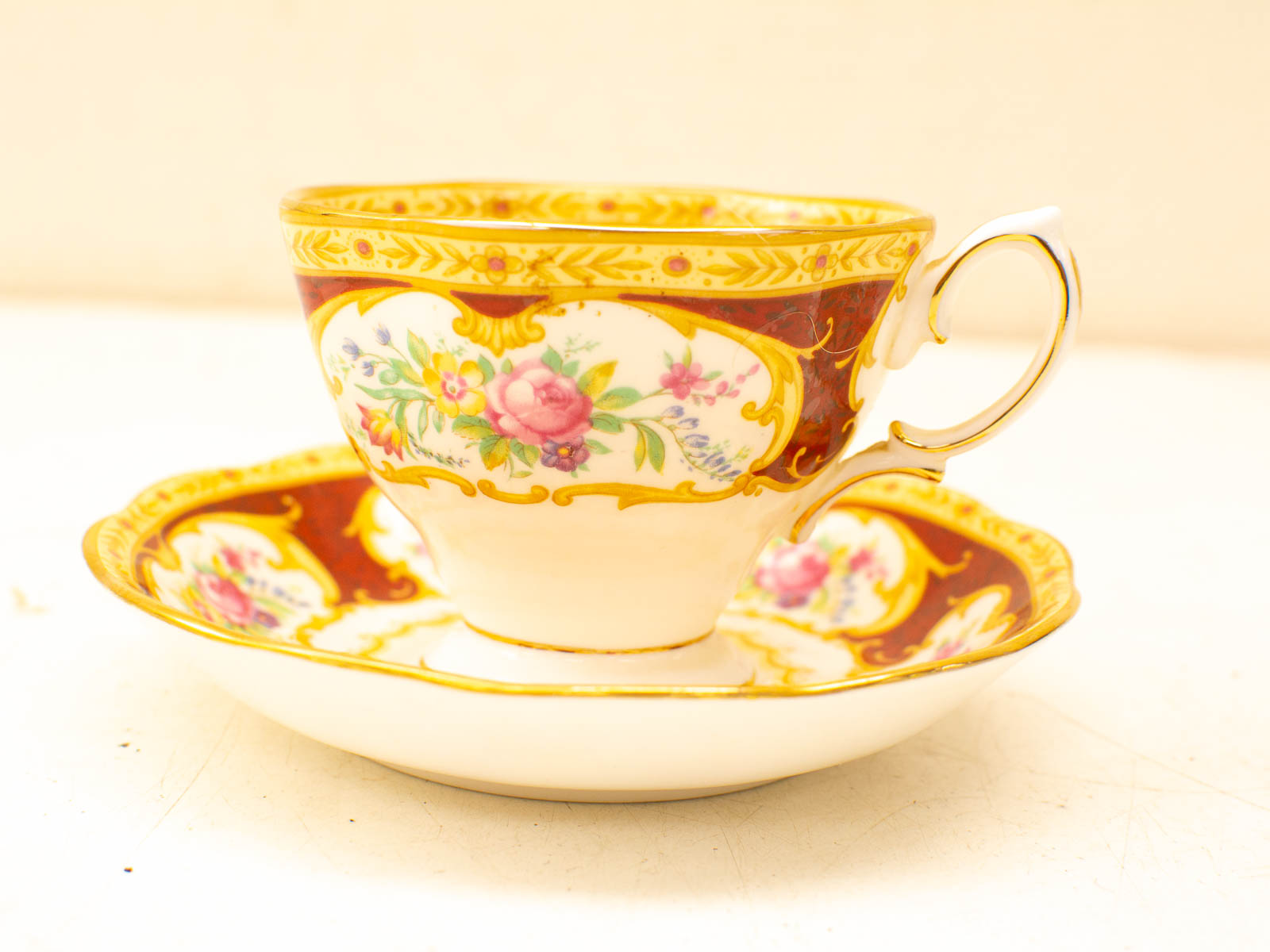 Elegant burgundy tea cup and saucer with floral patterns and gold accents for refined gatherings.