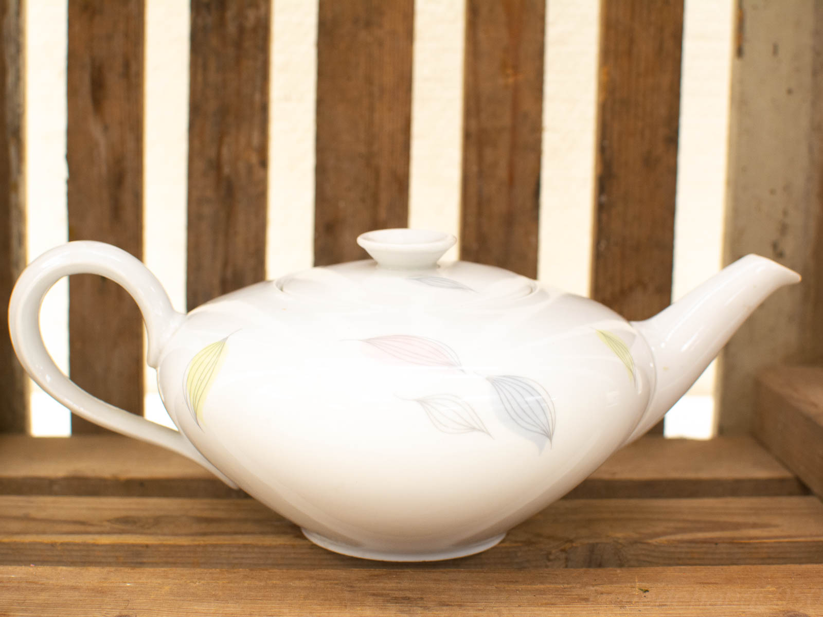 Timeless vintage porcelain teapot with pastel leaf designs, perfect for elegant tea gatherings.