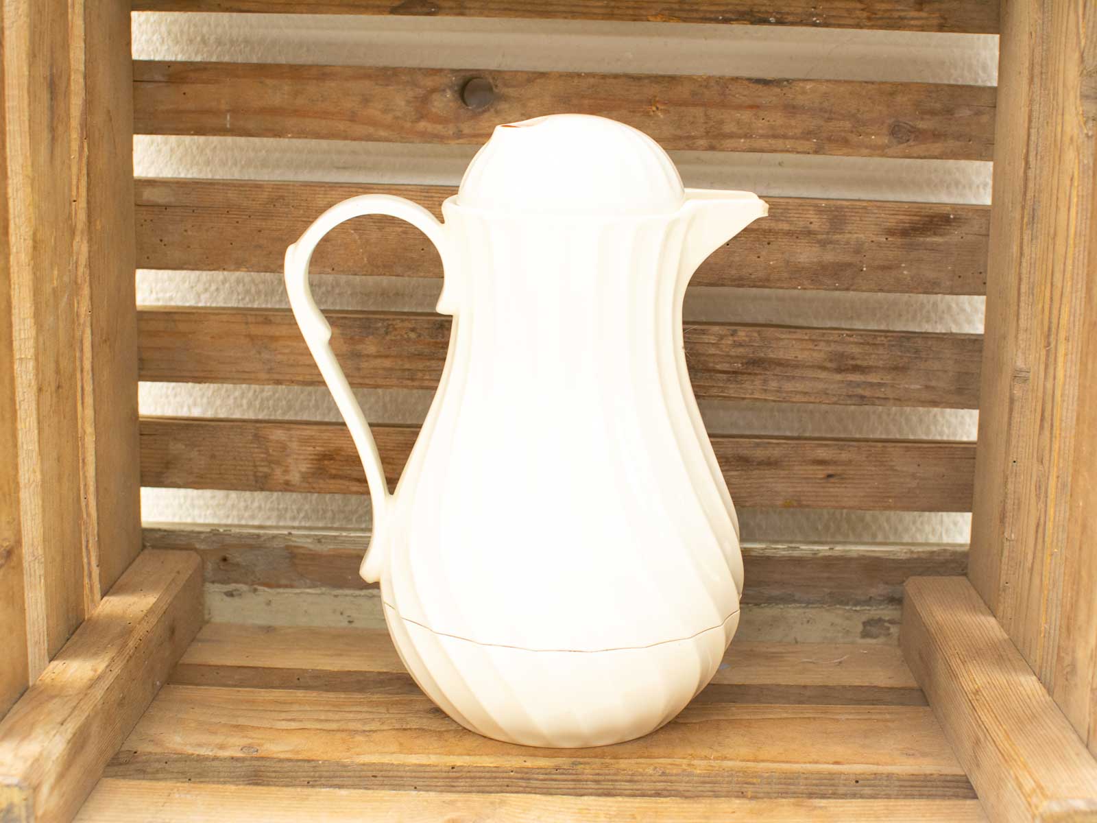 Elegant white pitcher on a rustic wood crate, perfect for enhancing home decor.