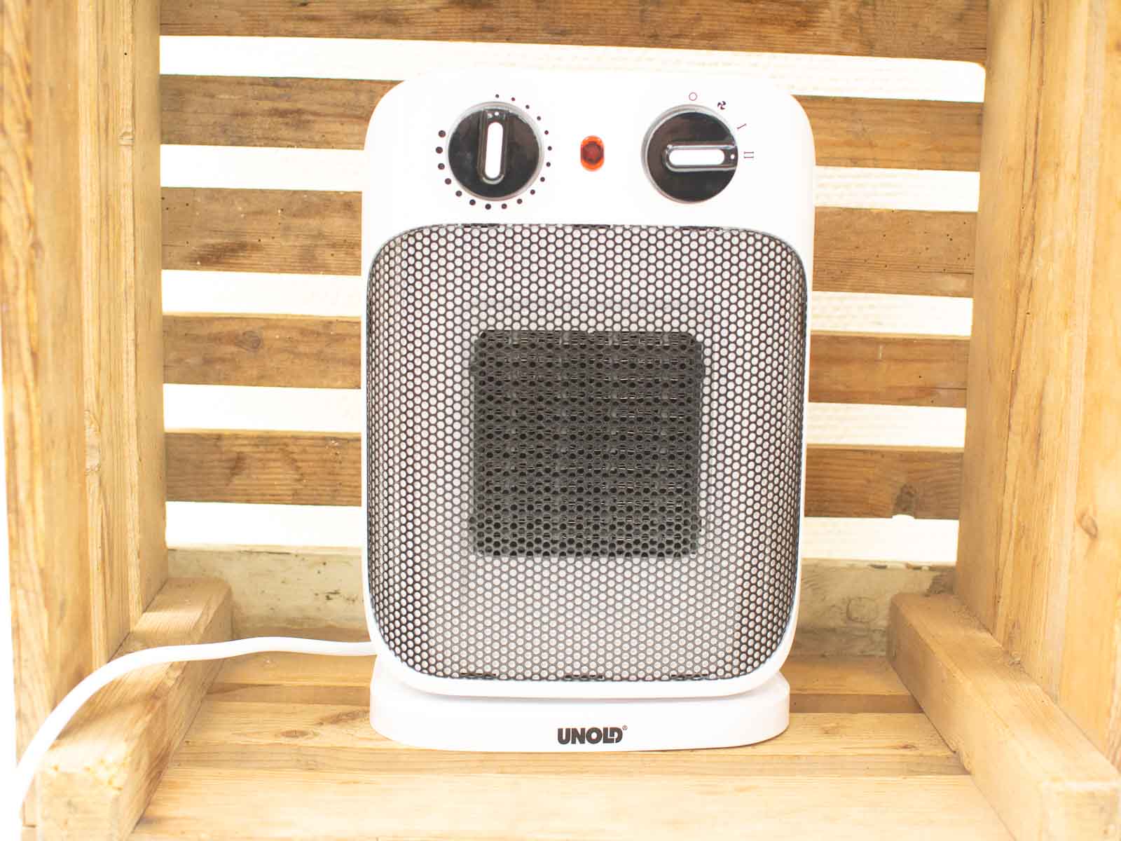 Sleek white electric heater against rustic wood, perfect for cozy indoor warmth during winter.