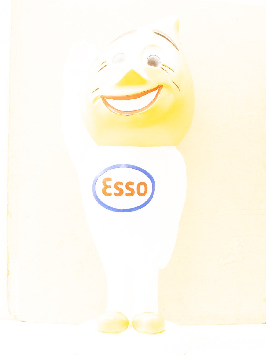 Cheerful Esso mascot in white suit, yellow head, and welcoming wave, evoking nostalgia.