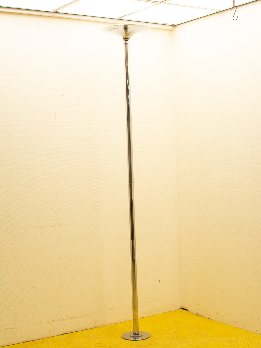 Sleek dance pole in a bright, minimalist studio with vibrant yellow flooring.