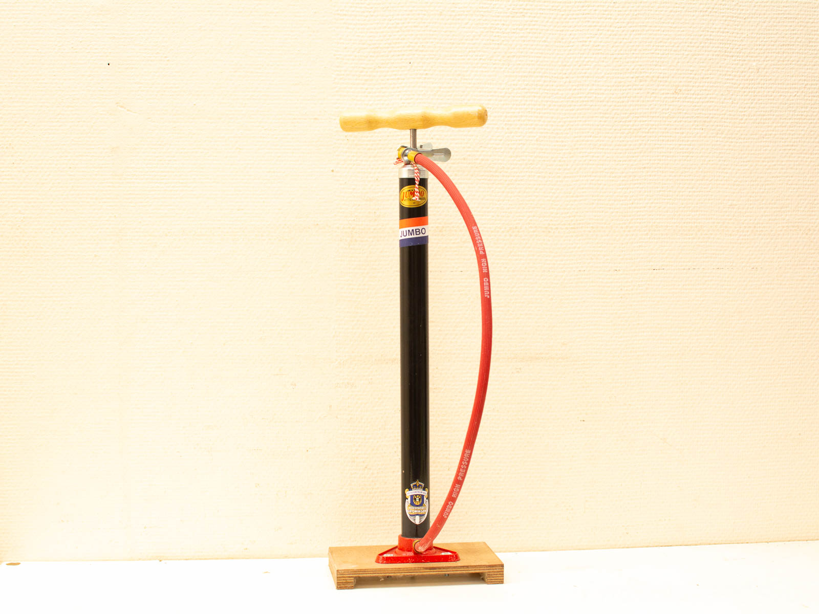 Ergonomic Jumbo bicycle pump with wooden handle and flexible red hose for efficient tire inflation.