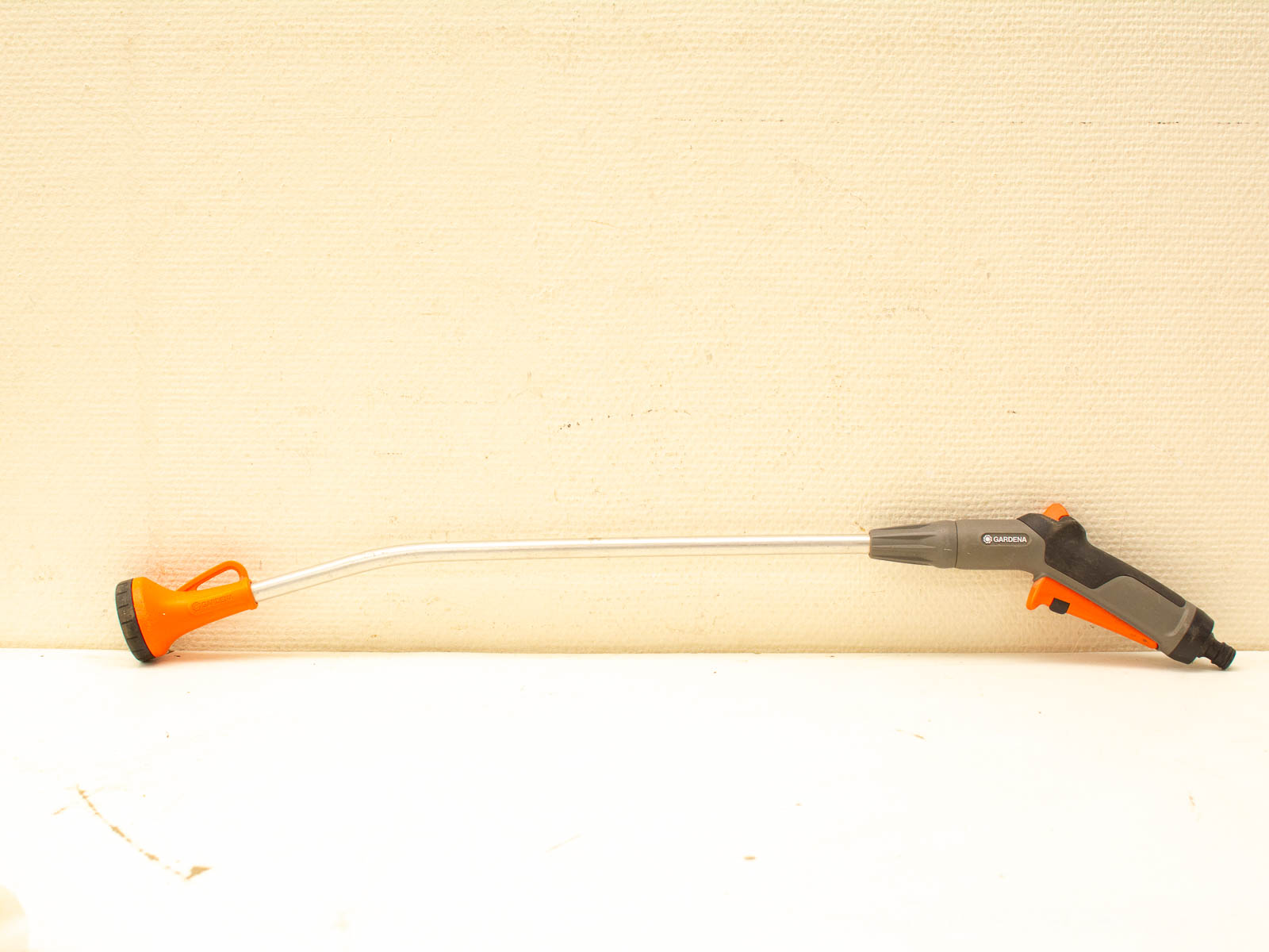 Ergonomic metal hose nozzle with orange handle for comfortable, efficient watering in gardens.