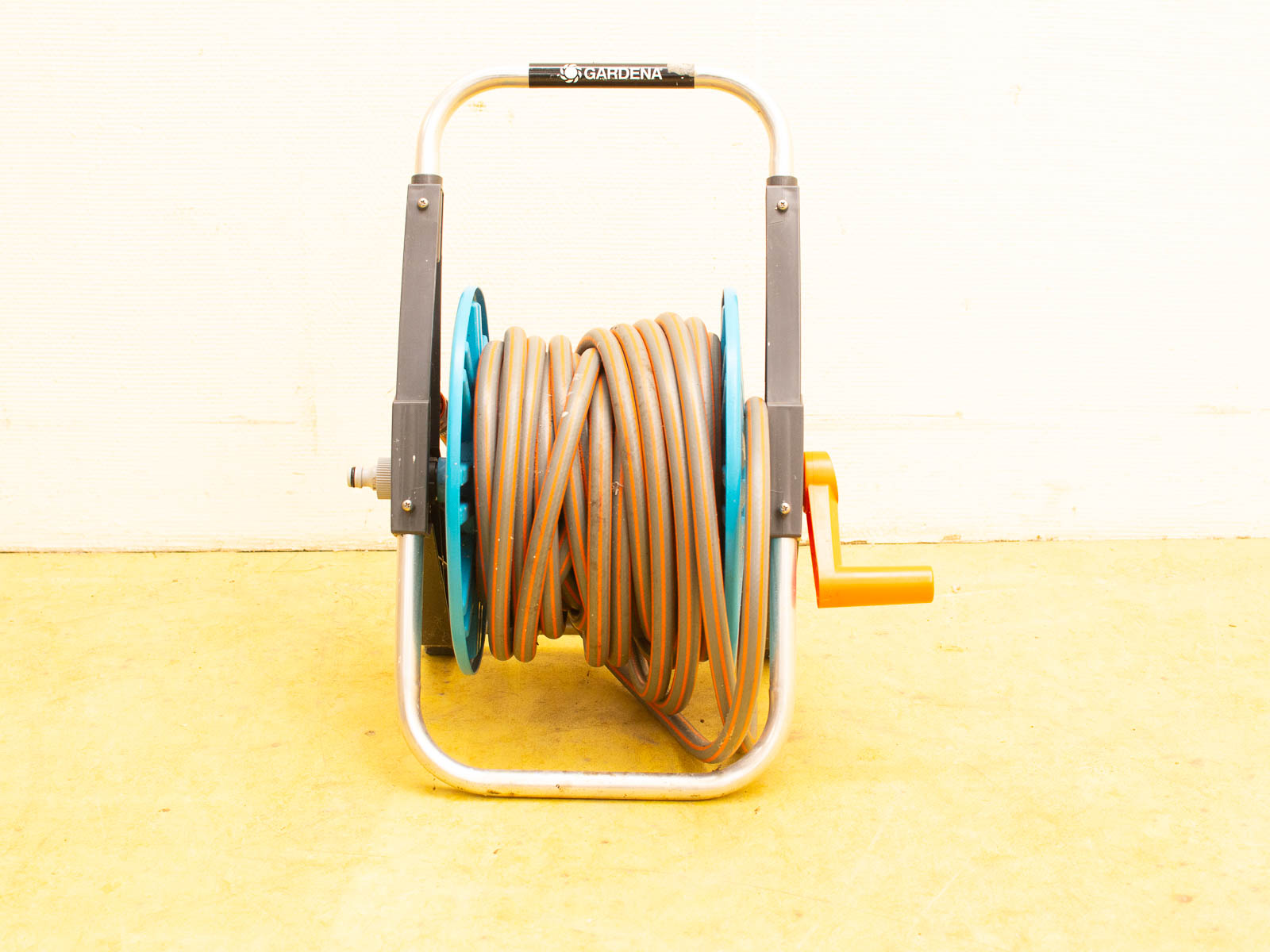 Durable garden hose reel with vibrant orange hose and blue base, perfect for outdoor use.