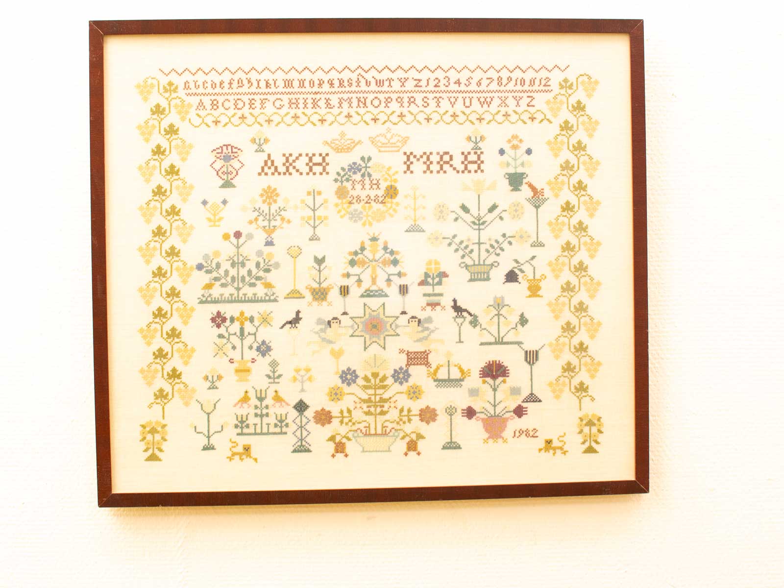 Vibrant 1982 floral sampler art, showcasing intricate embroidery and charming animal motifs.