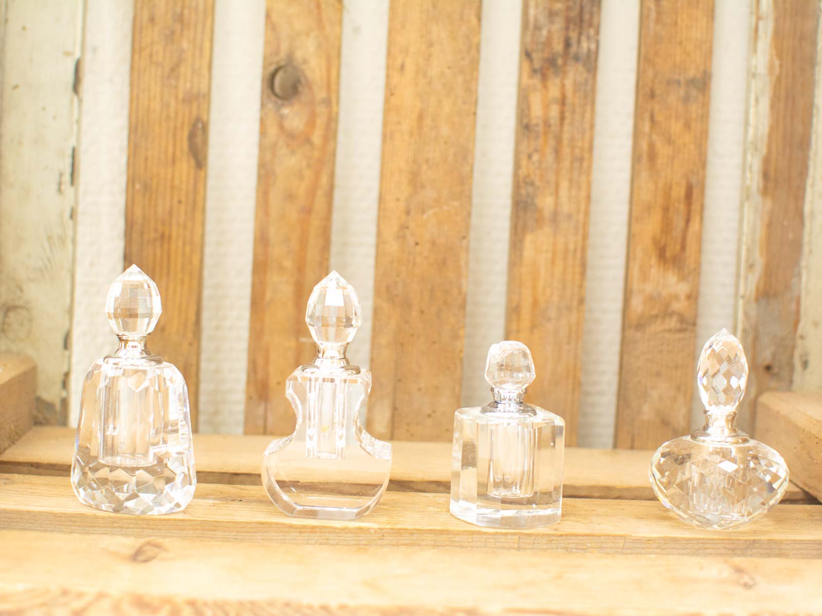 Elegant crystal bottles on rustic wood, showcasing unique designs and beautiful light reflections.