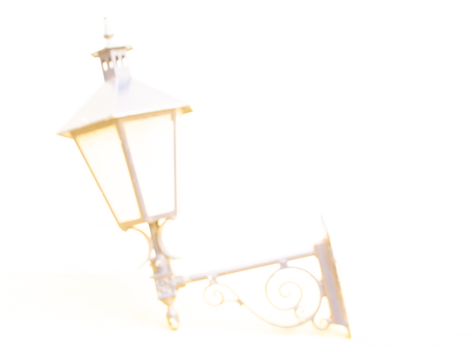 Elegant vintage street lamp radiating charm, despite overexposure, reminiscent of quaint urban scenery.