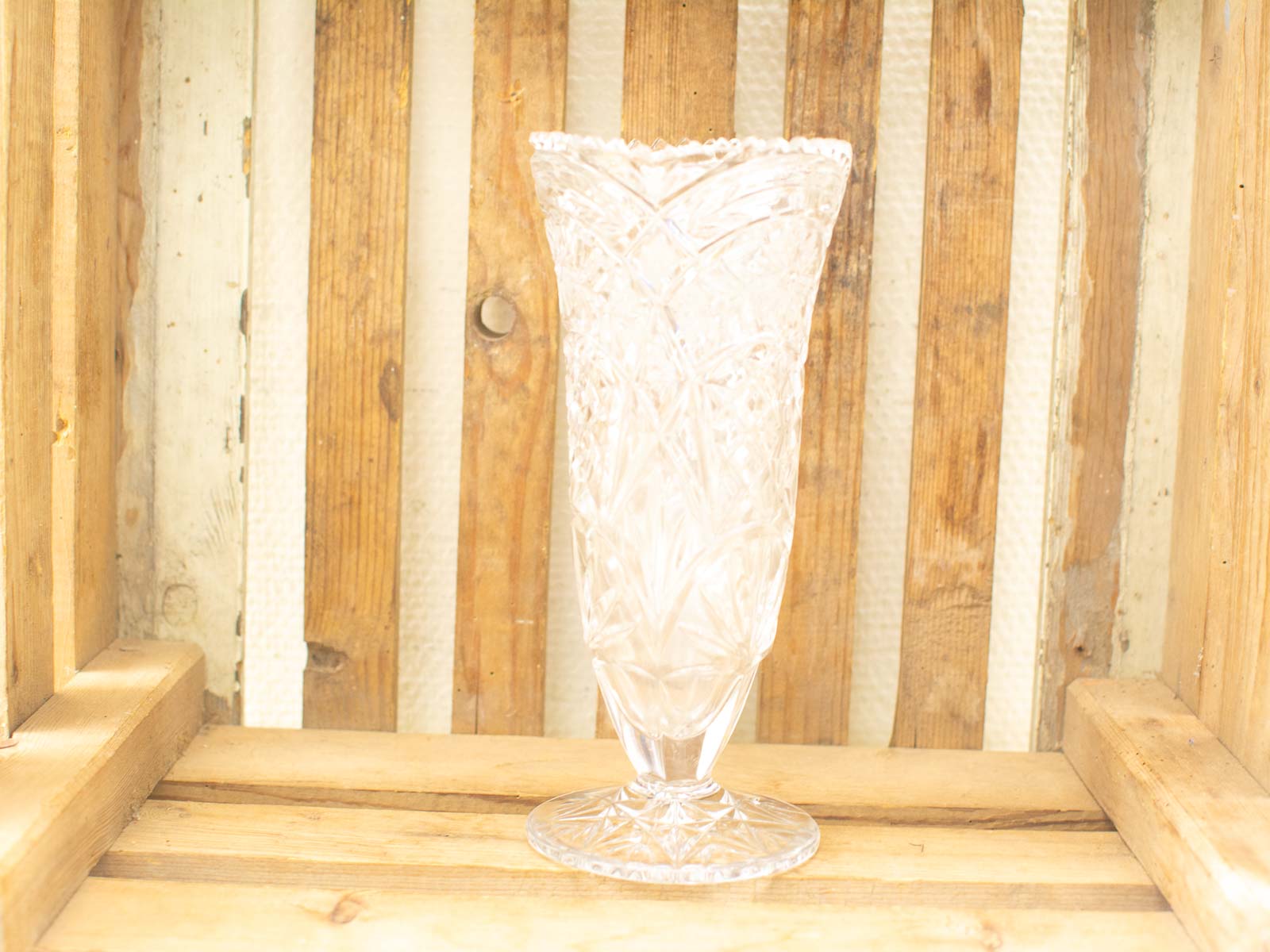 Elegant glass vase with geometric patterns against a rustic wooden background, perfect for home decor.