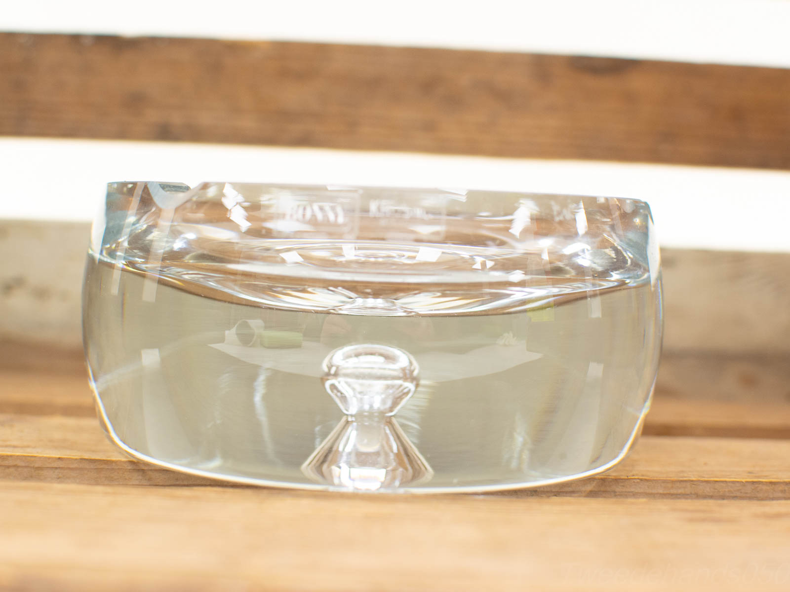 Elegant glass bowl with water on rustic wooden surface, showcasing modern design and natural charm.