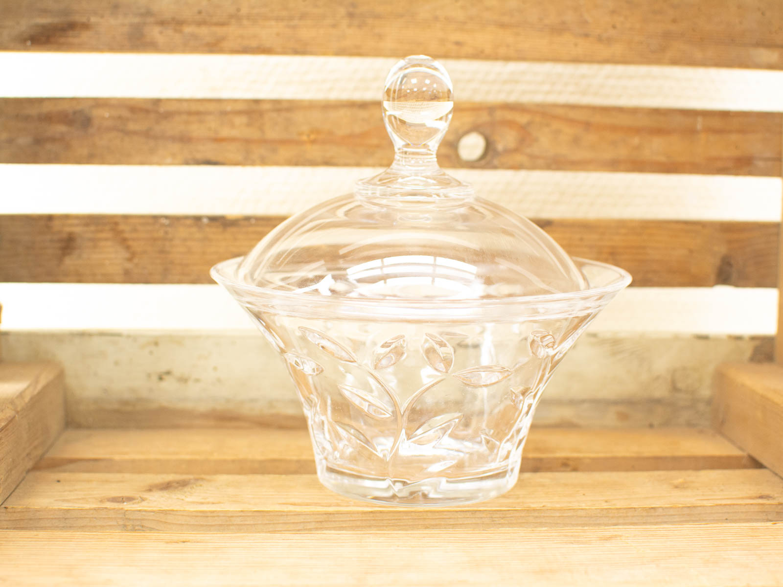 Elegant glass storage container with leaf patterns and dome lid, perfect for decor or treats.