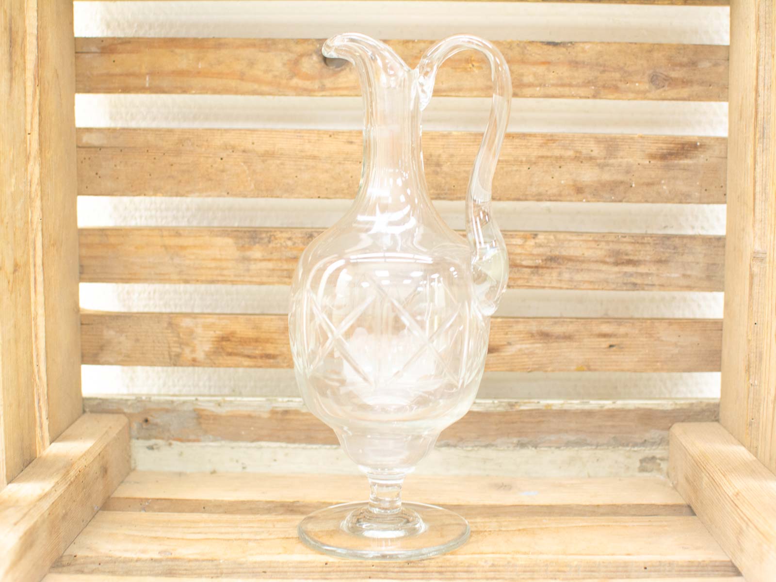 Elegant glass pitcher with diamond patterns against a rustic wooden backdrop, perfect for home decor.