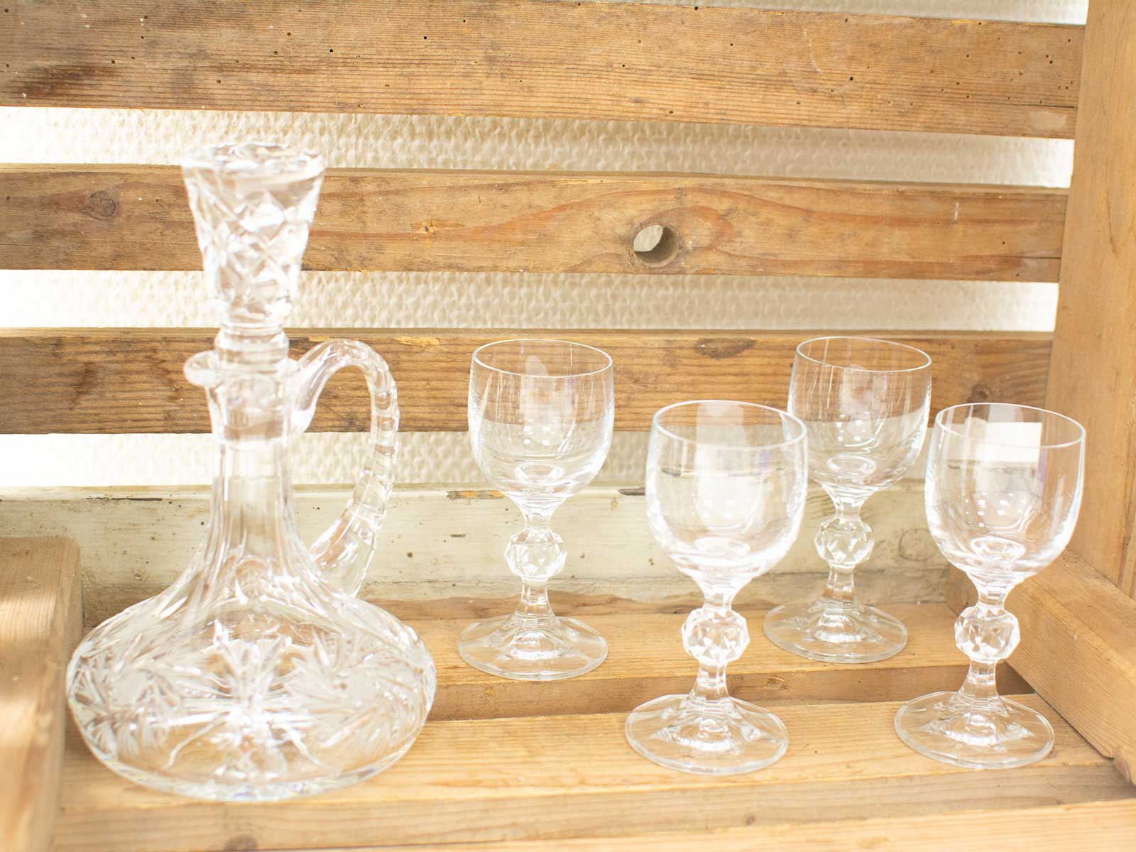 Elegant crystal decanter and glasses on rustic wood backdrop, showcasing fine craftsmanship and warmth.