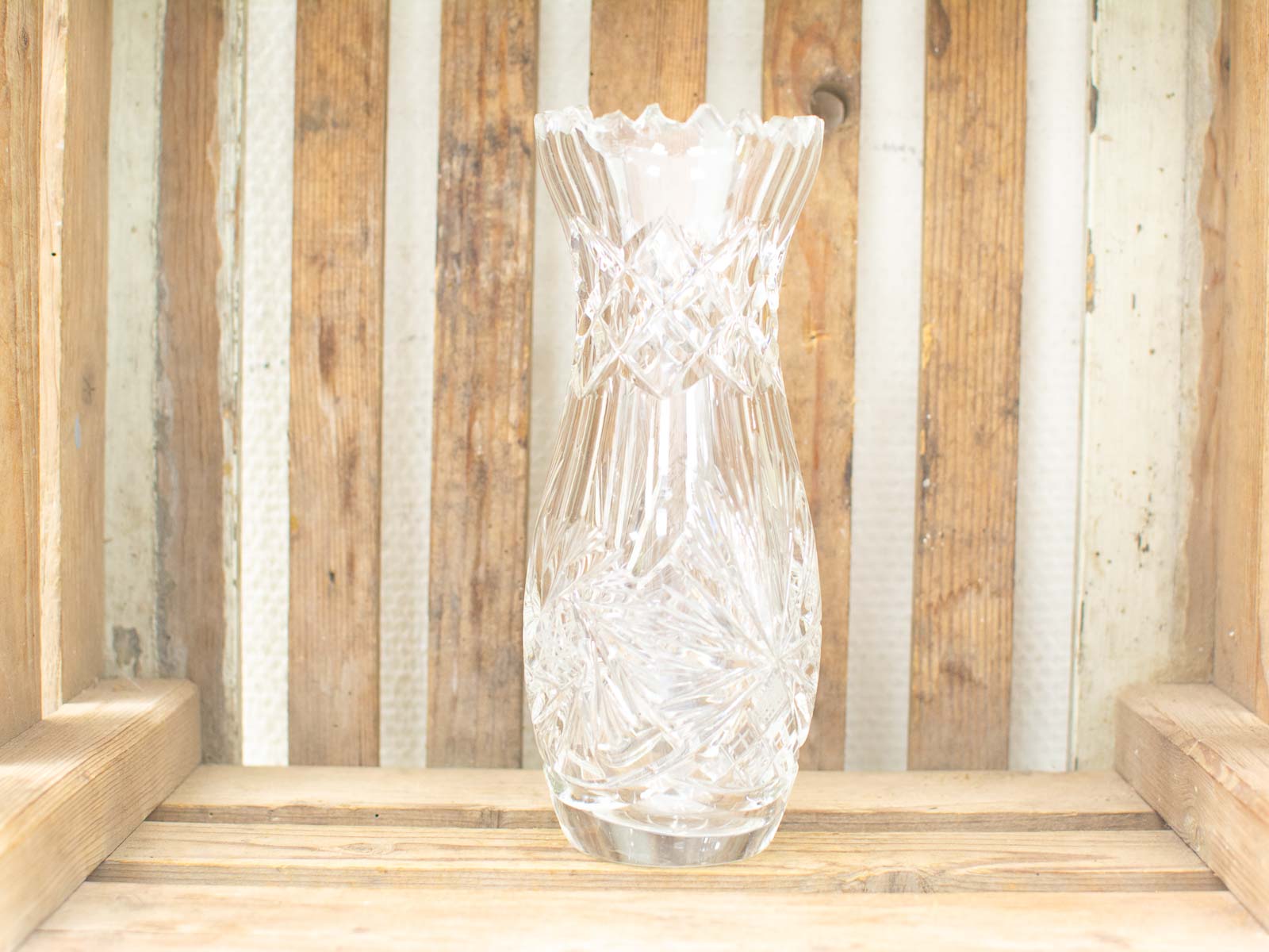 Elegant crystal vase with diamond cuts, set against a rustic wooden background. Perfect for decor.