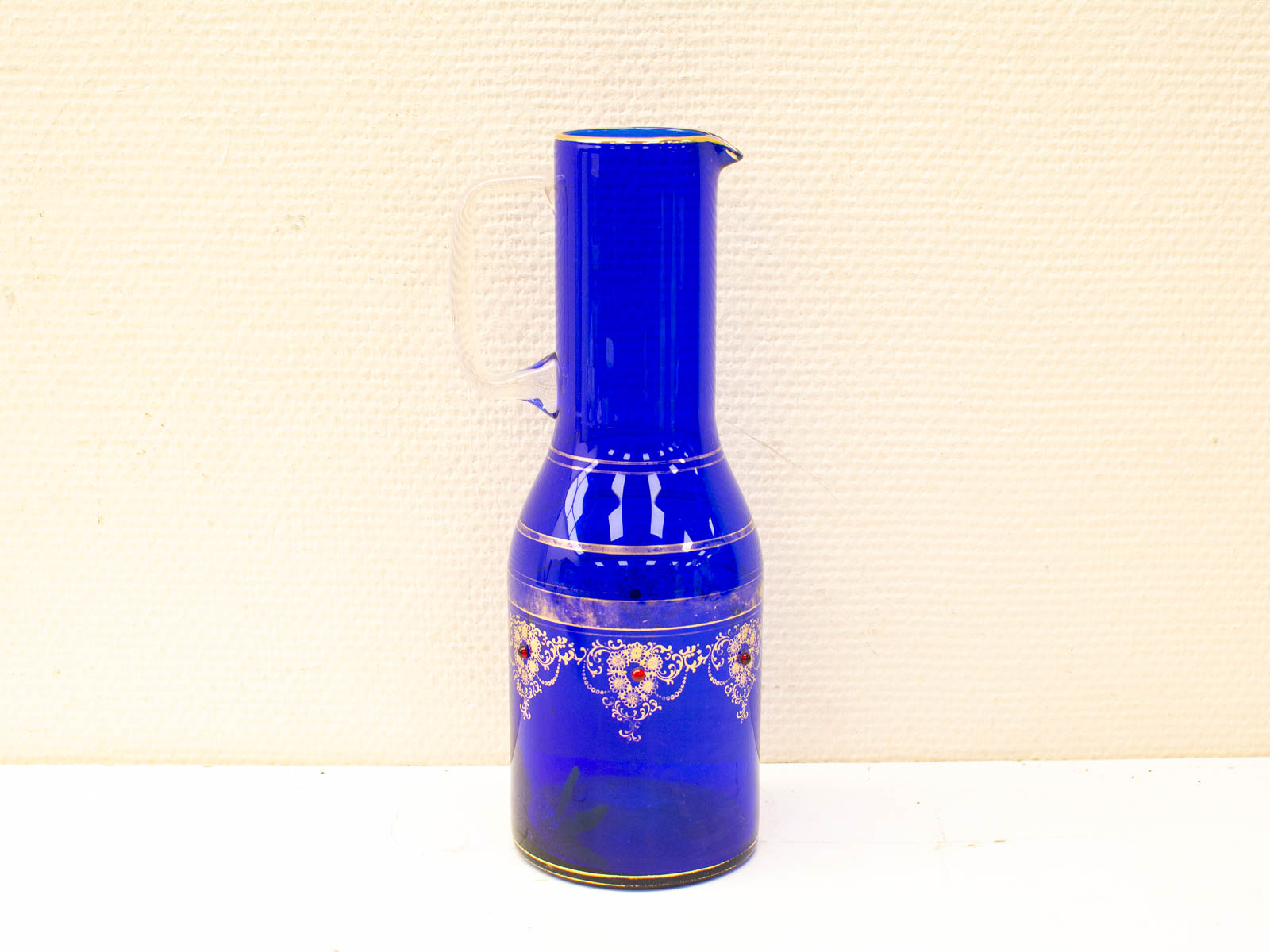 Vibrant blue vintage pitcher with gold floral details, perfect for decor or special occasions.