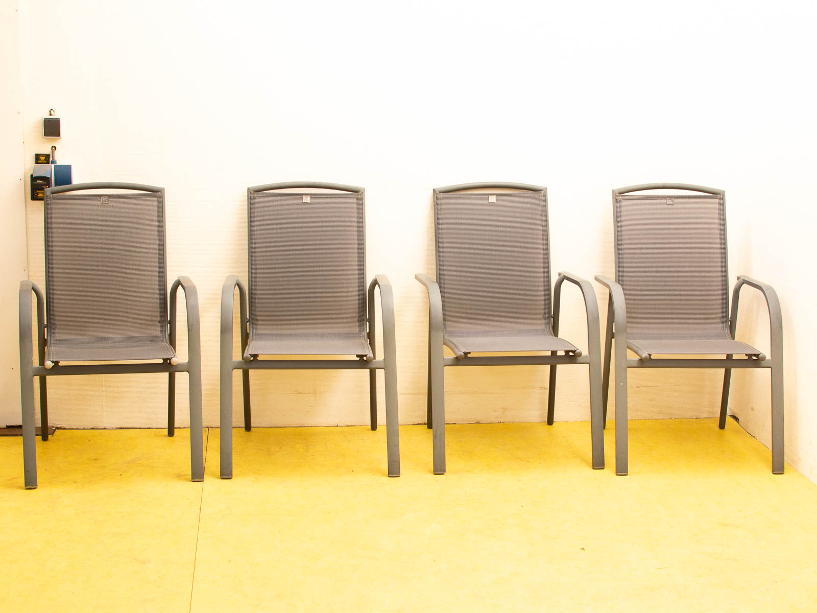 Modern gray chairs on a bright yellow floor against a clean white wall.