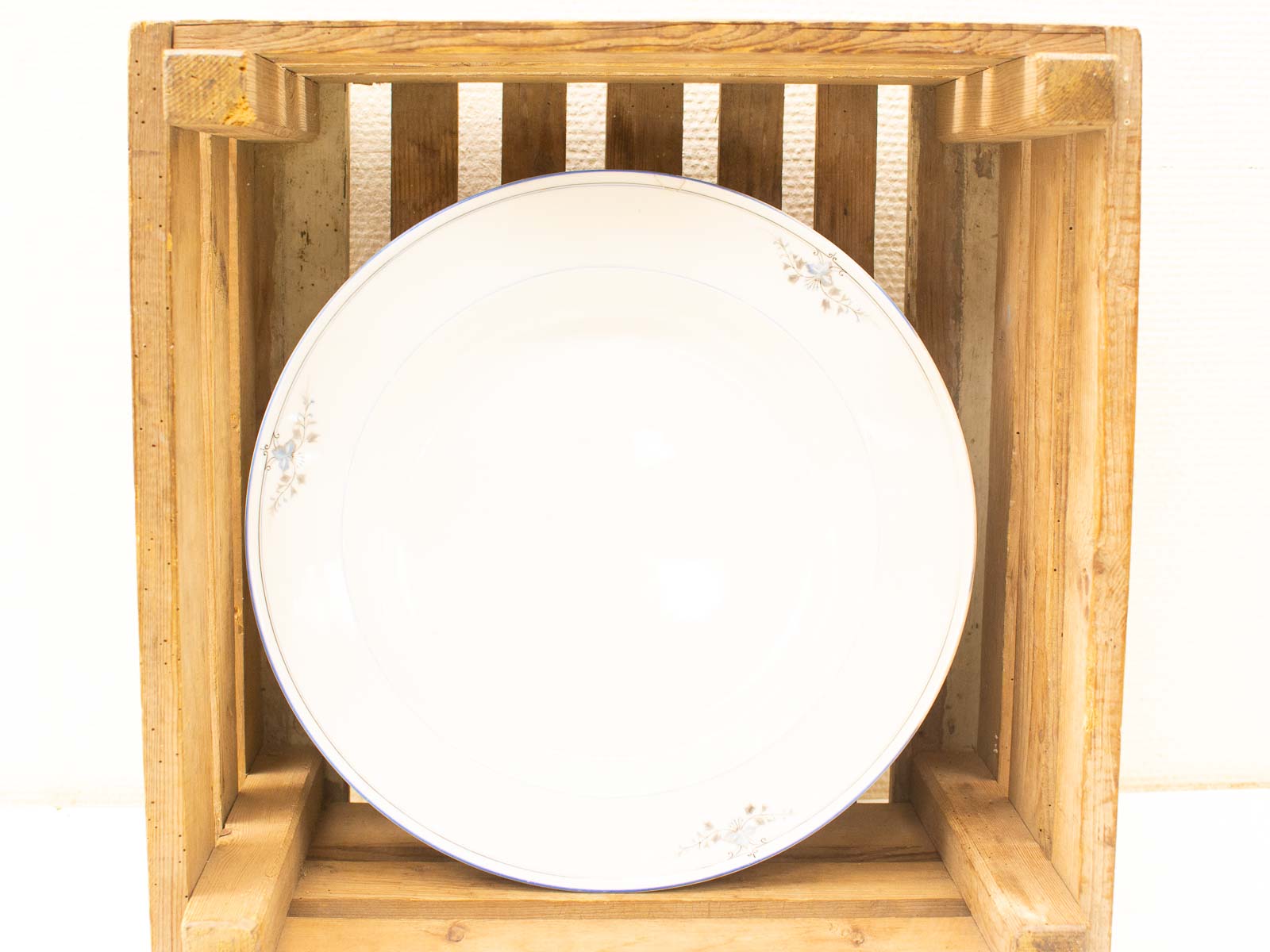 Elegant porcelain plate in rustic wooden crate, showcasing craftsmanship and timeless beauty.