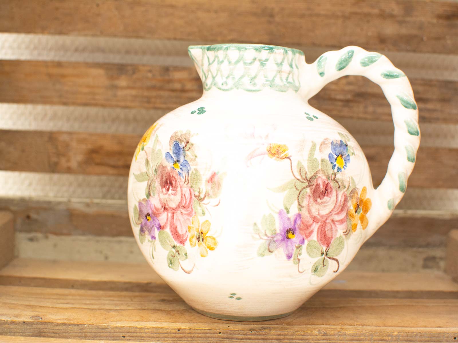 Elegant vintage ceramic pitcher with vibrant floral design and artisanal twisted handle. Perfect home decor!