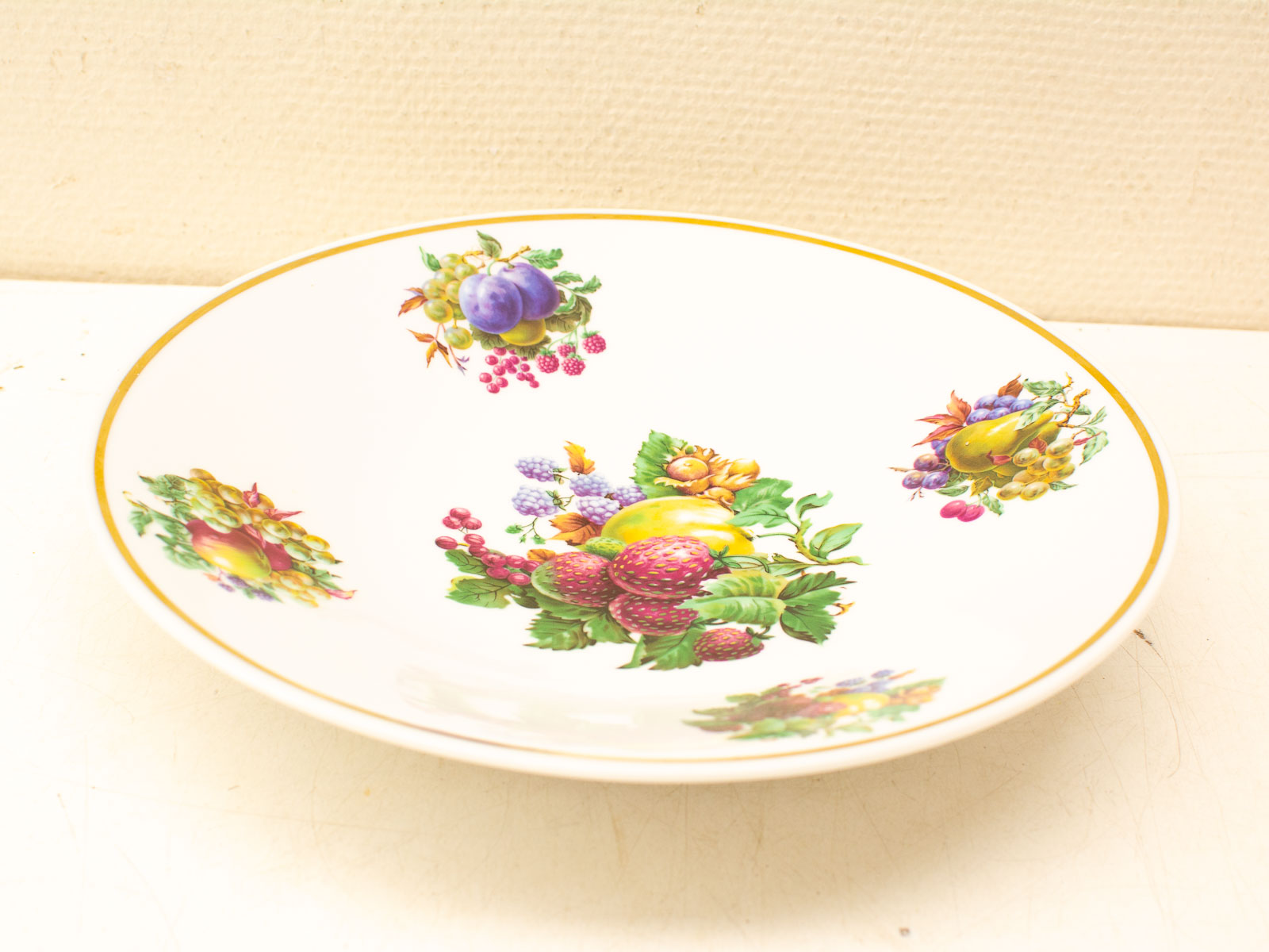 Elegant porcelain bowl with vibrant fruit designs and a luxurious golden rim. Perfect centerpiece.