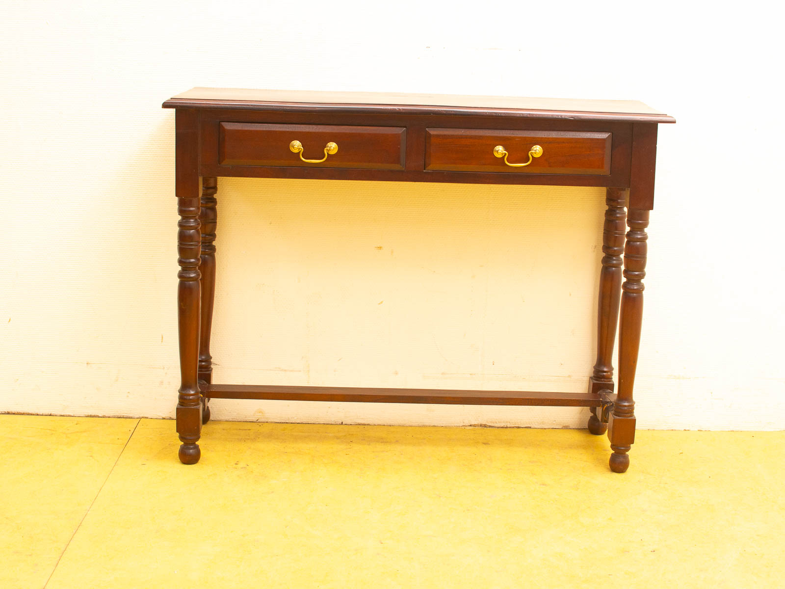 Elegant vintage wooden console table with brass handles and intricately turned legs, perfect for any decor.